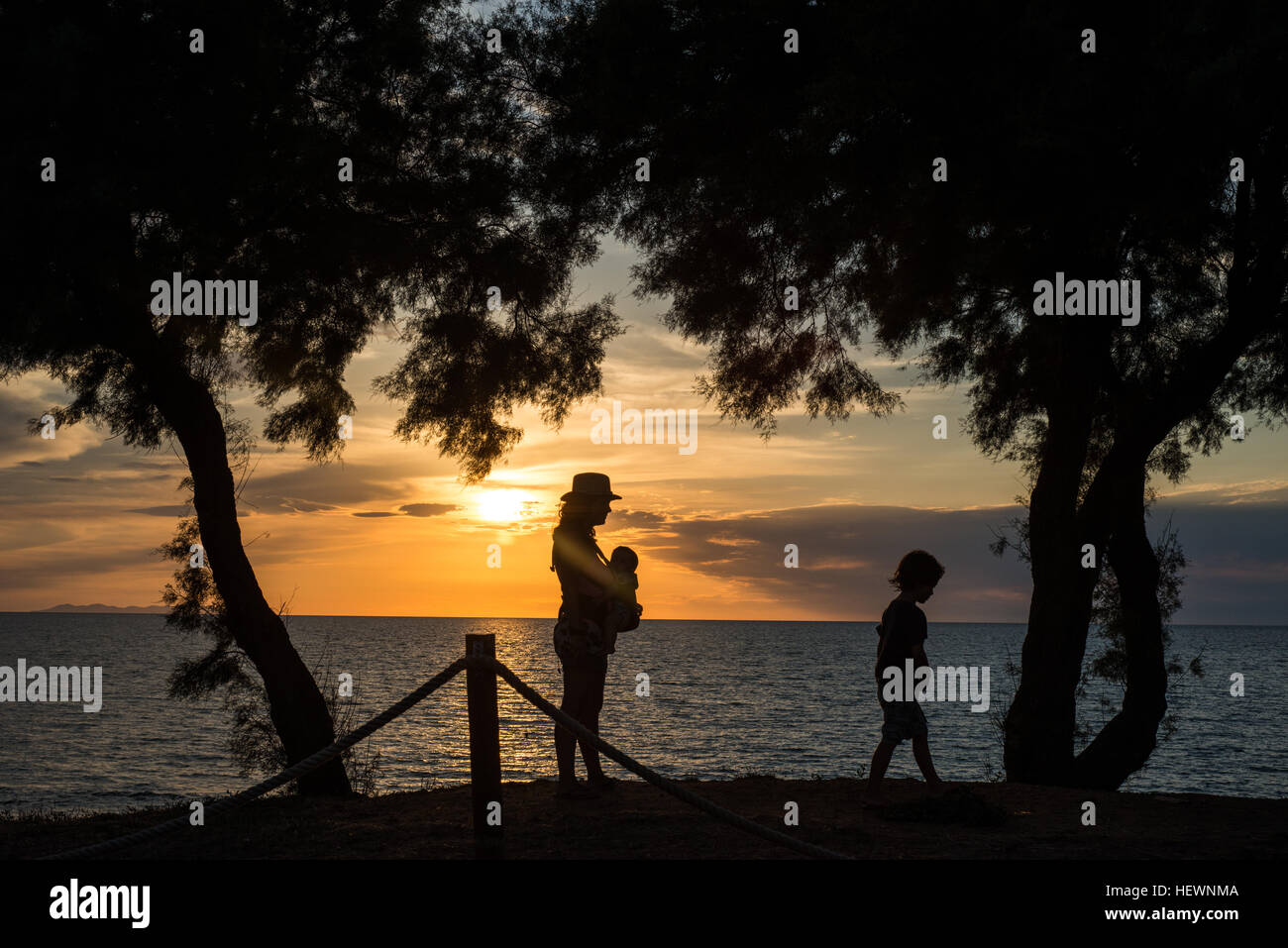Silhouette von Mutter und Kindern durch Wasser bei Sonnenuntergang, Italien Stockfoto