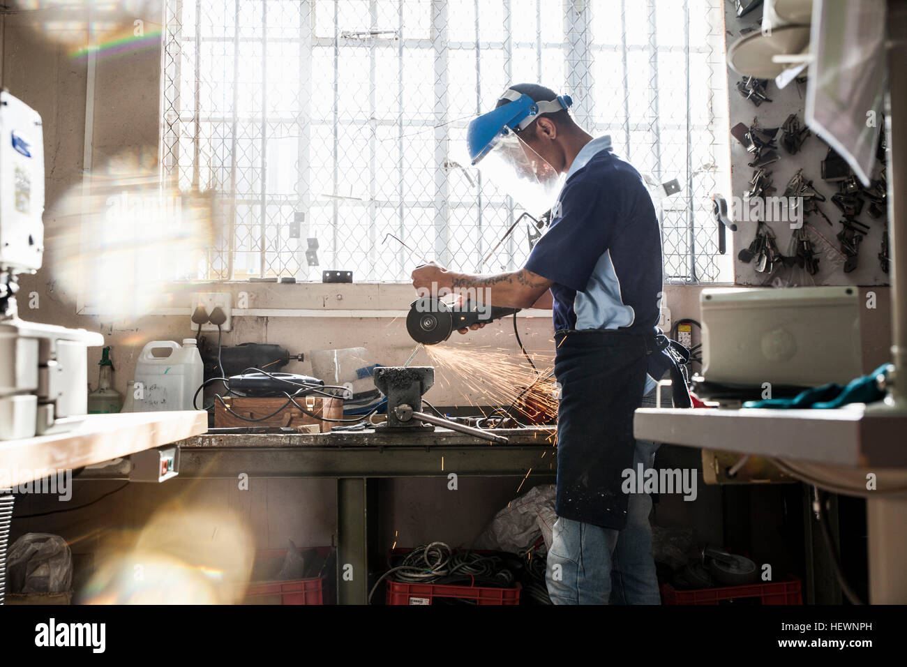 Junger Mann mit Winkelschleifer an Vize-in Reparatur-Werkstatt Stockfoto