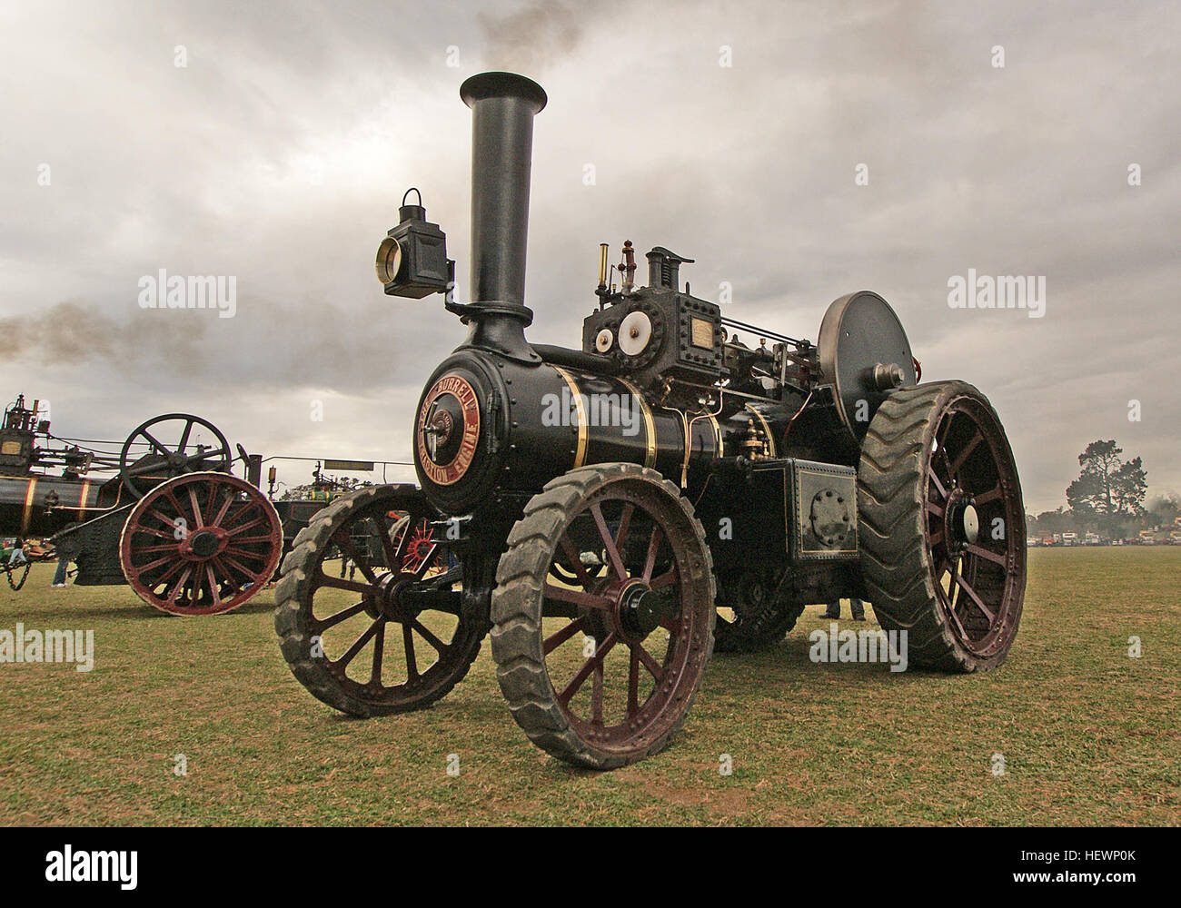 Die Burrell Traction Engine, eine dampfbetriebene Maschine, wird bei einer alten Landwirtschaftsrallye in Aktion fotografiert. Dieses historische Fahrzeug ist bekannt für seine rote Farbe und den robusten Dampfmotor und repräsentiert die Kraft und Innovation früherer Landmaschinen. Zugmaschinen wie diese waren für das Pflügen von Feldern und den Gütertransport im späten 19. Und frühen 20. Jahrhundert von entscheidender Bedeutung. Stockfoto