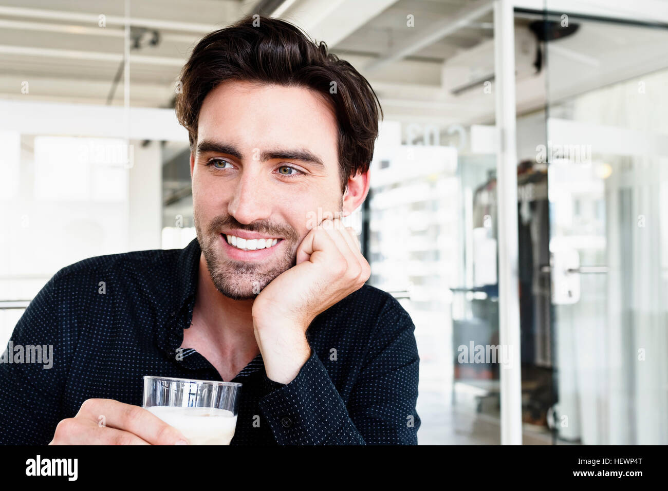 Mann mit Hand am Kinn, mit Glas Milch suchen Sie lächelnd Stockfoto