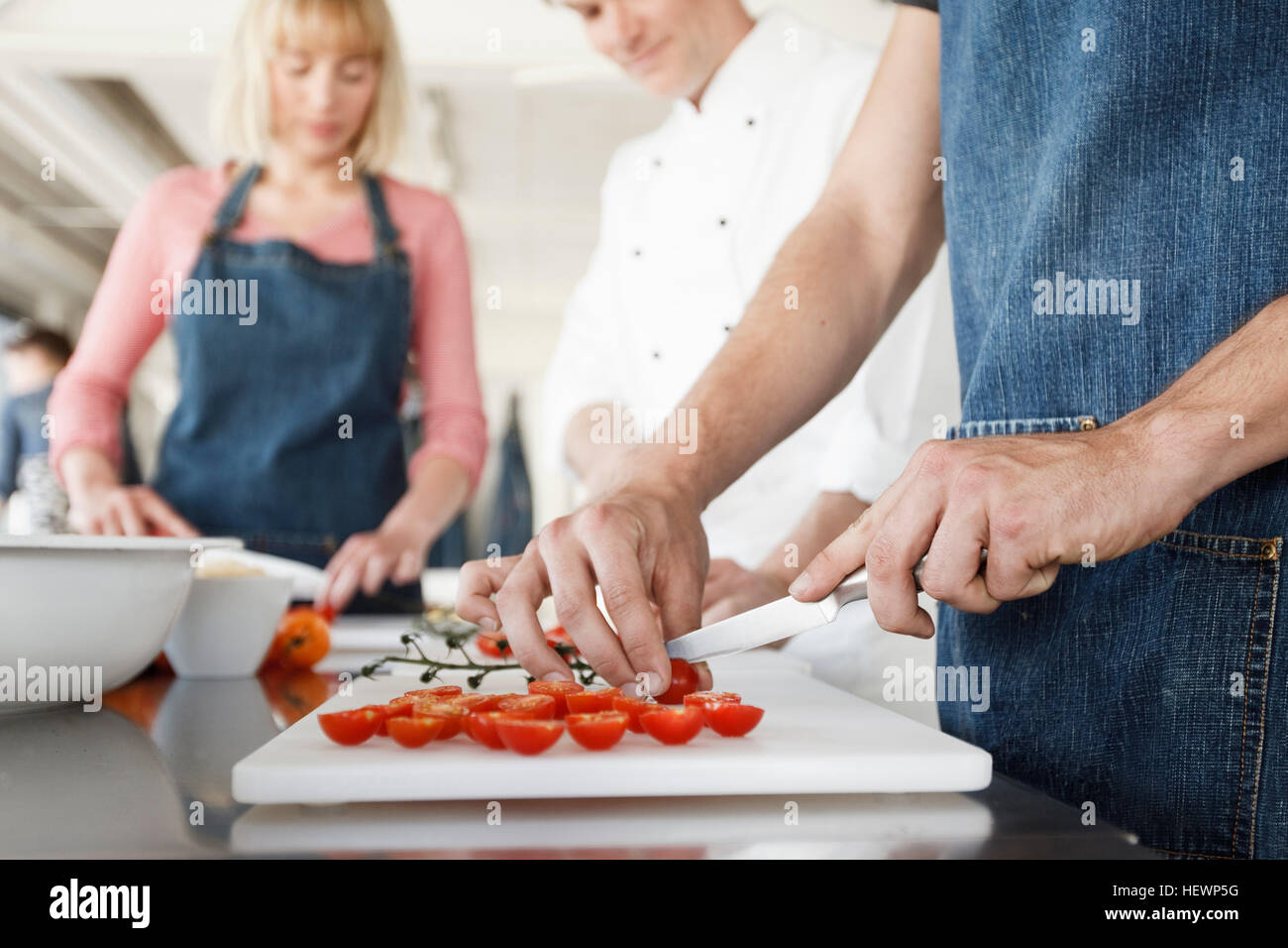 Koch und paar in Küche Tomaten schneiden Stockfoto