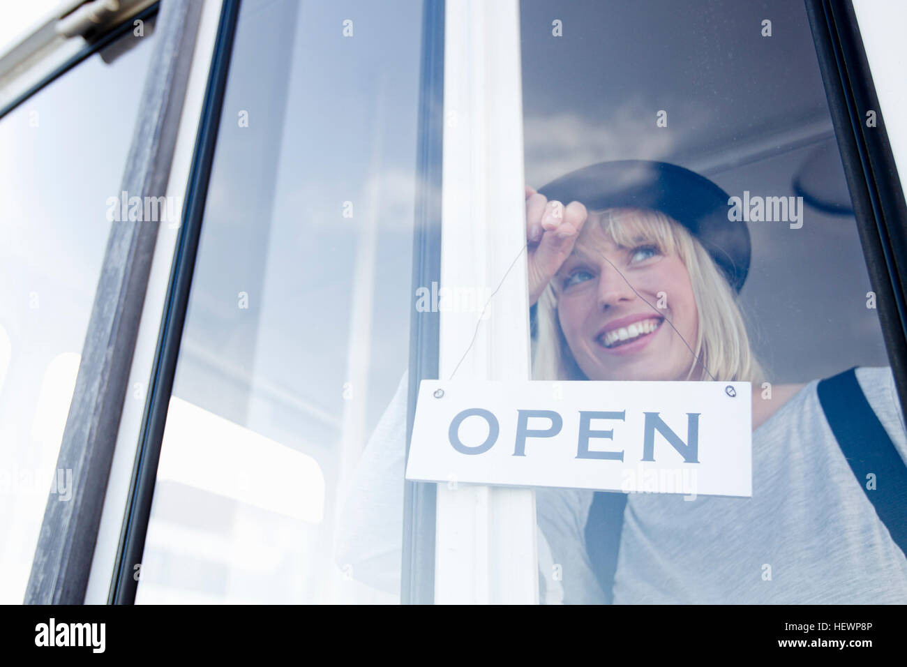 Frau platzieren offenen anmelden Glas Tür lächelnd Stockfoto