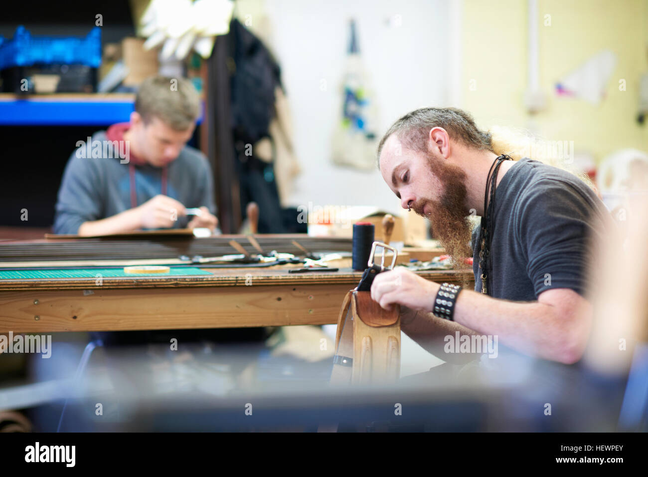 Männliche Arbeiter in Lederwerkstatt, Nähen Nähte um eine Gürtelschnalle Stockfoto
