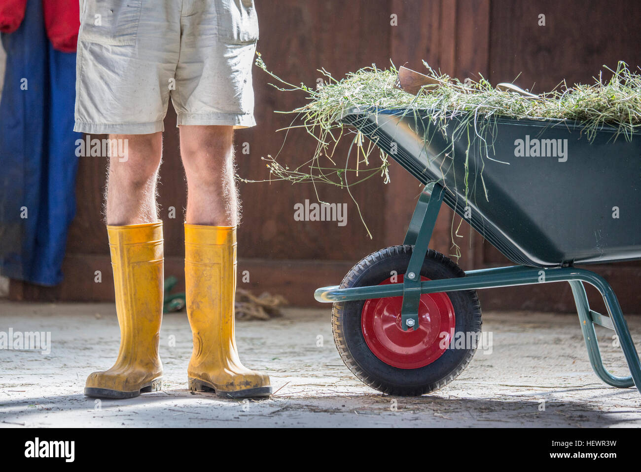 Taille abwärts Blick auf junge männliche Landarbeiter in gelben Latex Stiefel Stockfoto