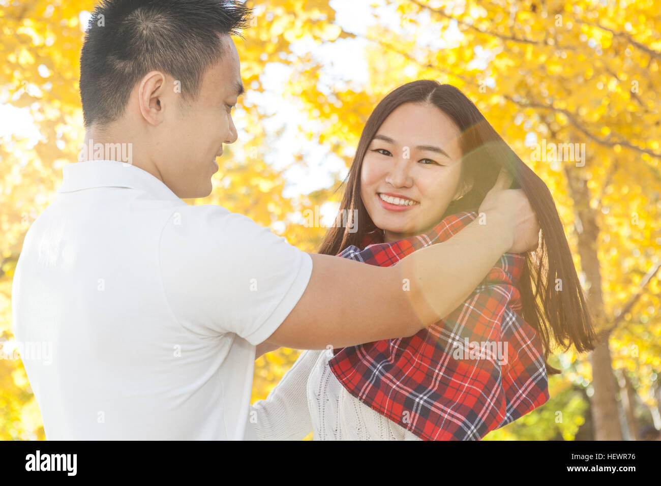 Junger Mann einwickeln Tartan Schal um Freundin im Herbst Park, Peking, China Stockfoto