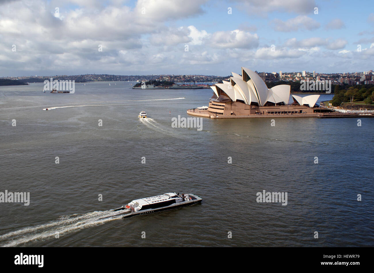 Dieses lebhafte Bild des Hafens von Sydney umfasst berühmte Wahrzeichen wie das Opernhaus von Sydney und die Harbour Bridge sowie die geschäftigen Fährgeschäfte von Captain Cook Cruises und Manly Ferries. Stockfoto