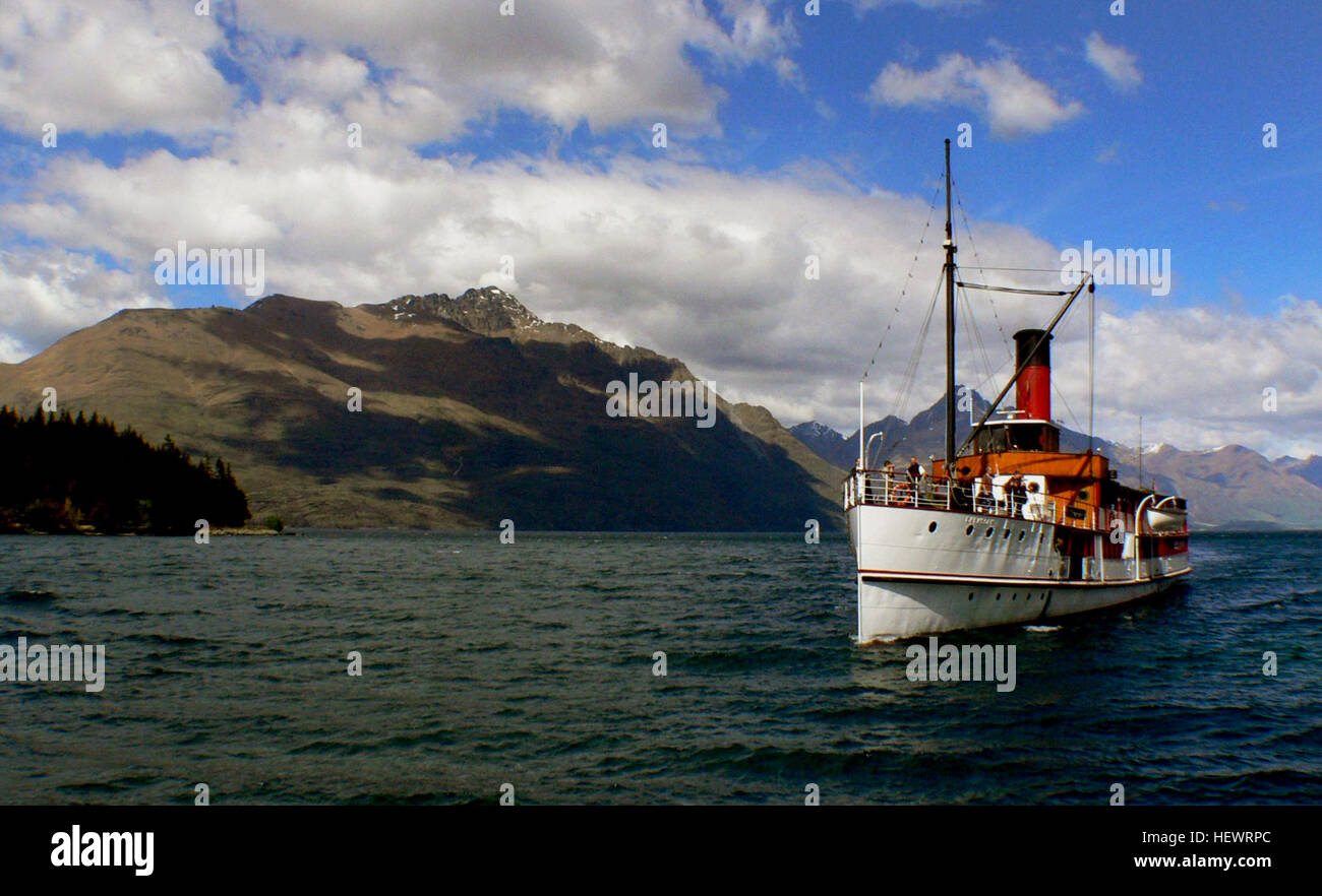 Das Dampfschiff TSS Earnslaw bietet eine nostalgische Kreuzfahrt über den Lake Wakatipu, wo Passagiere den Charme der alten Welt der dampfbetriebenen Fahrt erleben. Die Schiffsbrüder beteuern die Feuerboxen und tragen so zur historischen Atmosphäre bei. Stockfoto