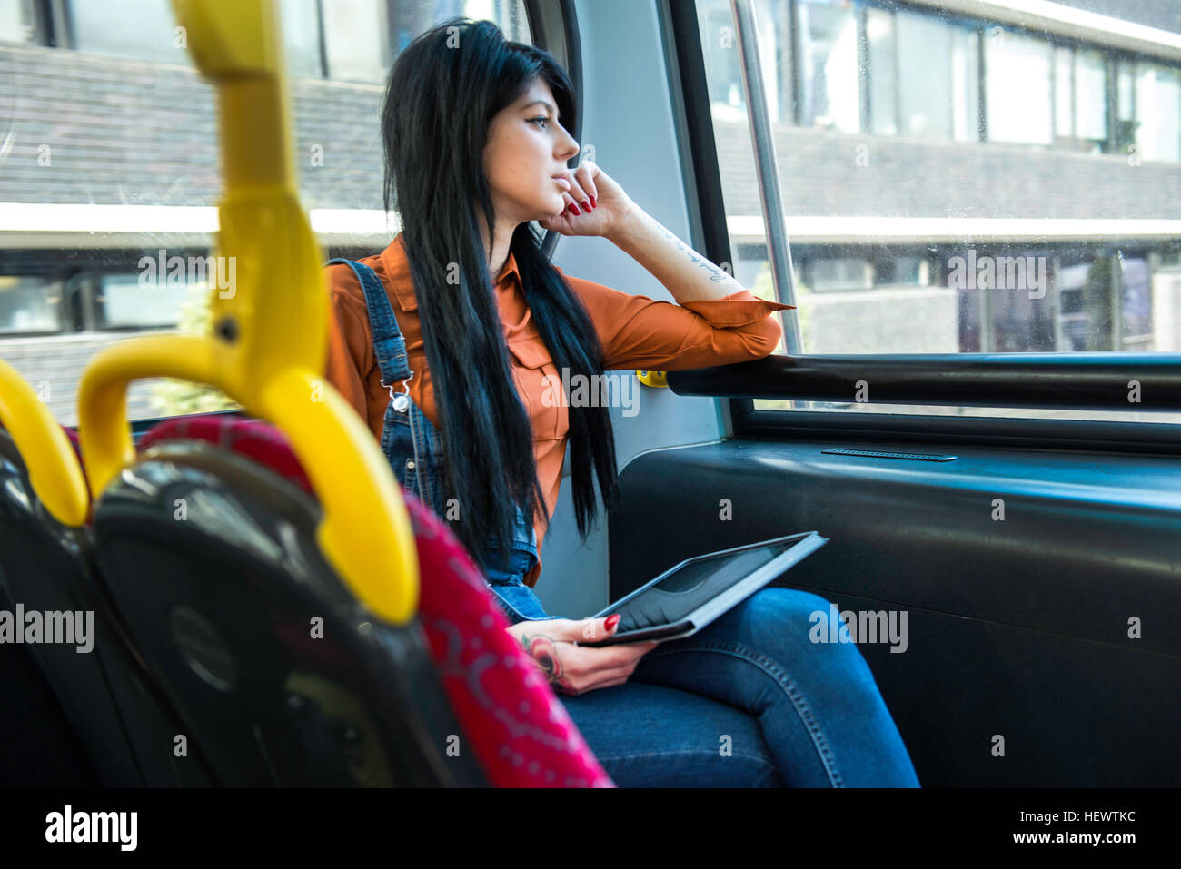 Junge Frau sitzt auf Bus, mit digital-Tablette, Blick aus Fenster Stockfoto