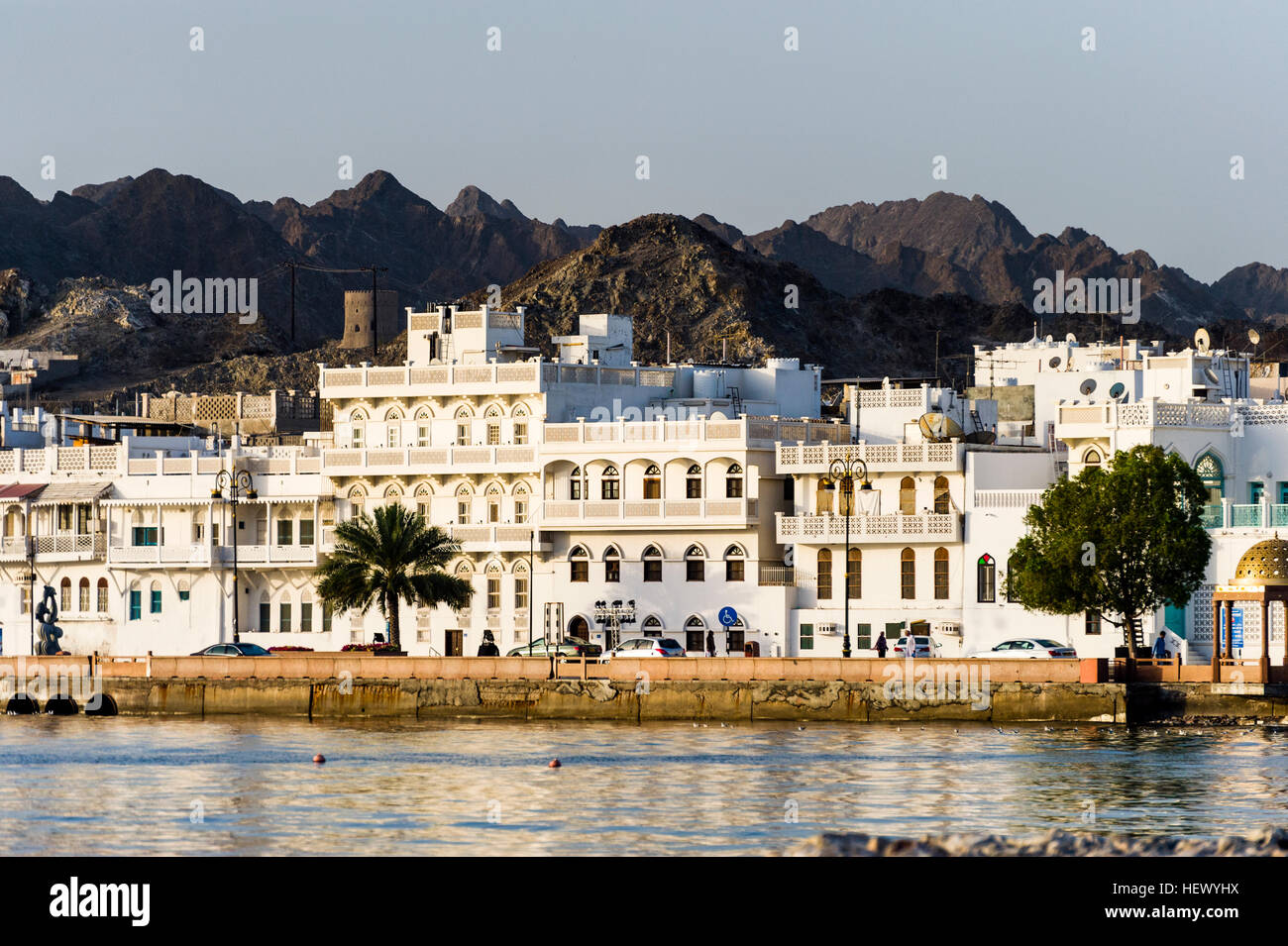 Wüste Berge überragen weiß getünchten Wänden des eine Einkaufs- und Hotel am Ufer des Golfs von Oman. Stockfoto