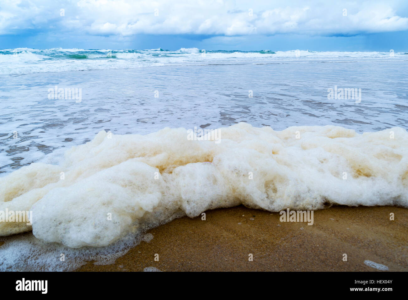 Schaum erzeugt durch Sturmwellen Welle rollt auf einem leeren Strand. Stockfoto