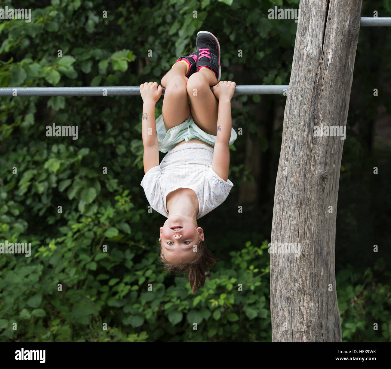 Mädchen von Monkey Bar kopfüber hängend Stockfoto