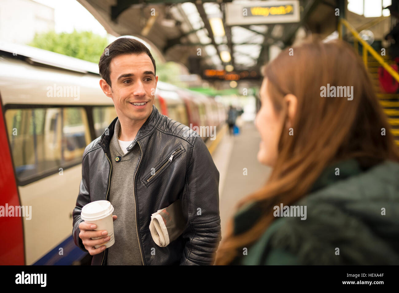 Paar am Bahnhof Plattform von Angesicht zu Angesicht lächelnd Stockfoto