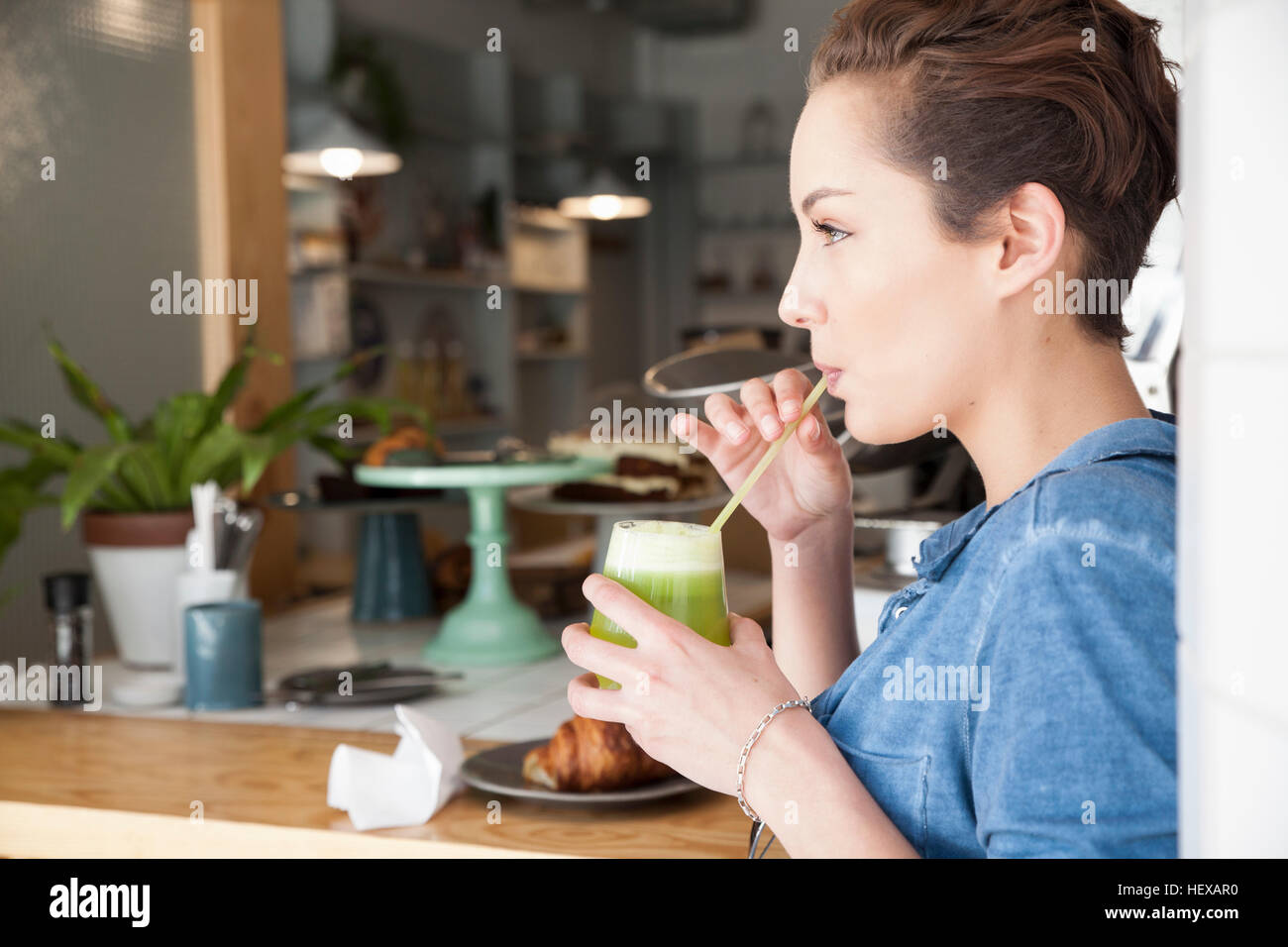 Junge Frau sitzt an Bar im Café, trinken mit Strohhalm trinken Stockfoto