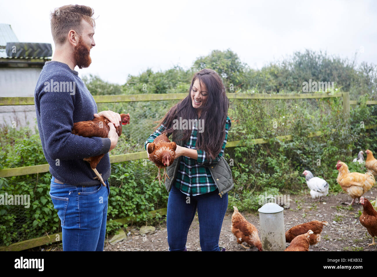 Junges Paar auf der Hühnerfarm halten Hühner Stockfoto