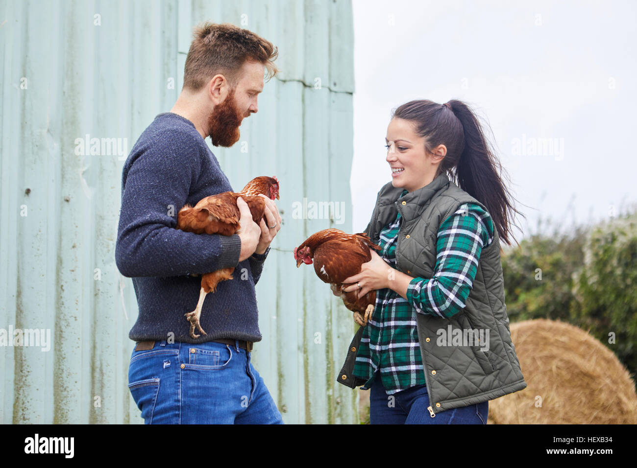 Junges Paar auf der Hühnerfarm halten Hühner Stockfoto