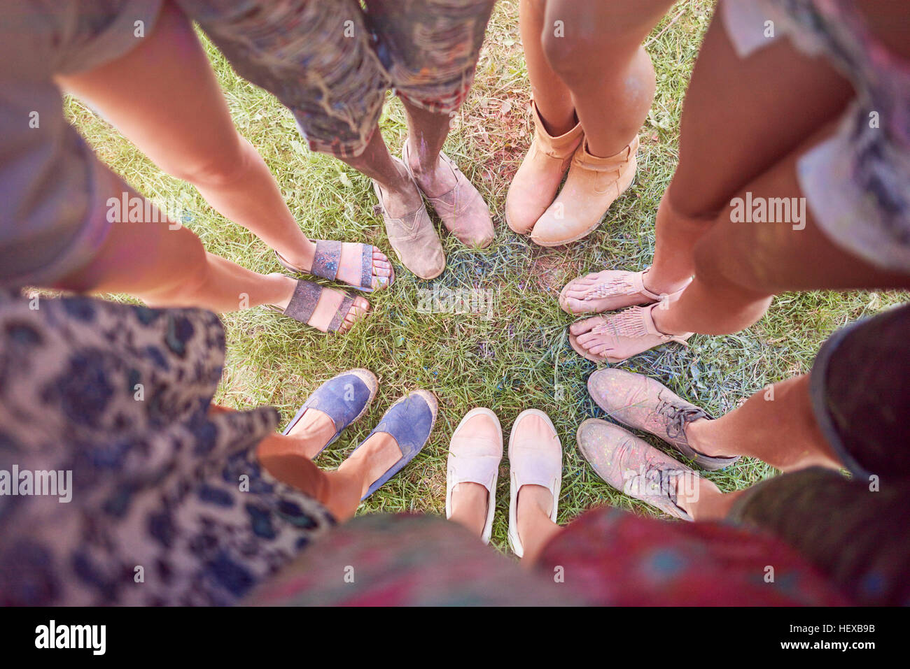Gruppe von Freunden am Festival, bedeckt in bunten Pulverlack, stehen im Kreis, erhöhten Blick auf Füße Stockfoto