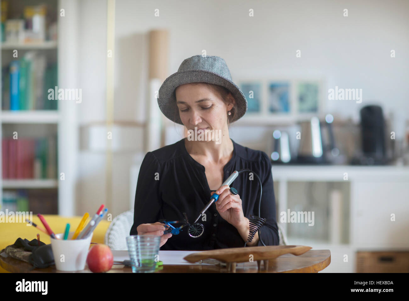 Reife Frau sitzt am Schreibtisch, mit Lötkolben Stockfoto