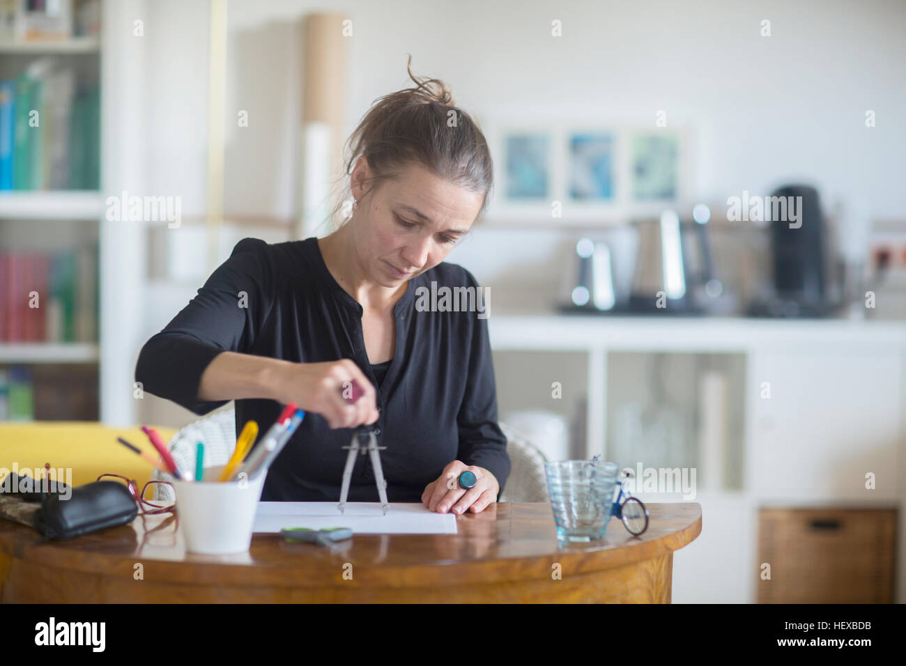 Reife Frau sitzt am Schreibtisch, mit Zirkel Stockfoto