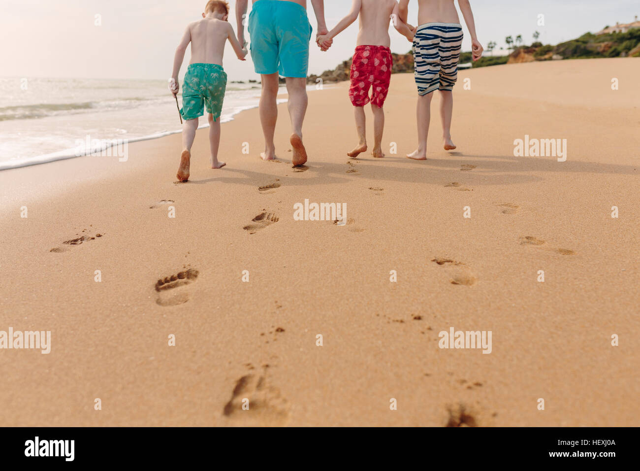 Vater und Söhne zu Fuß am Strand Stockfoto