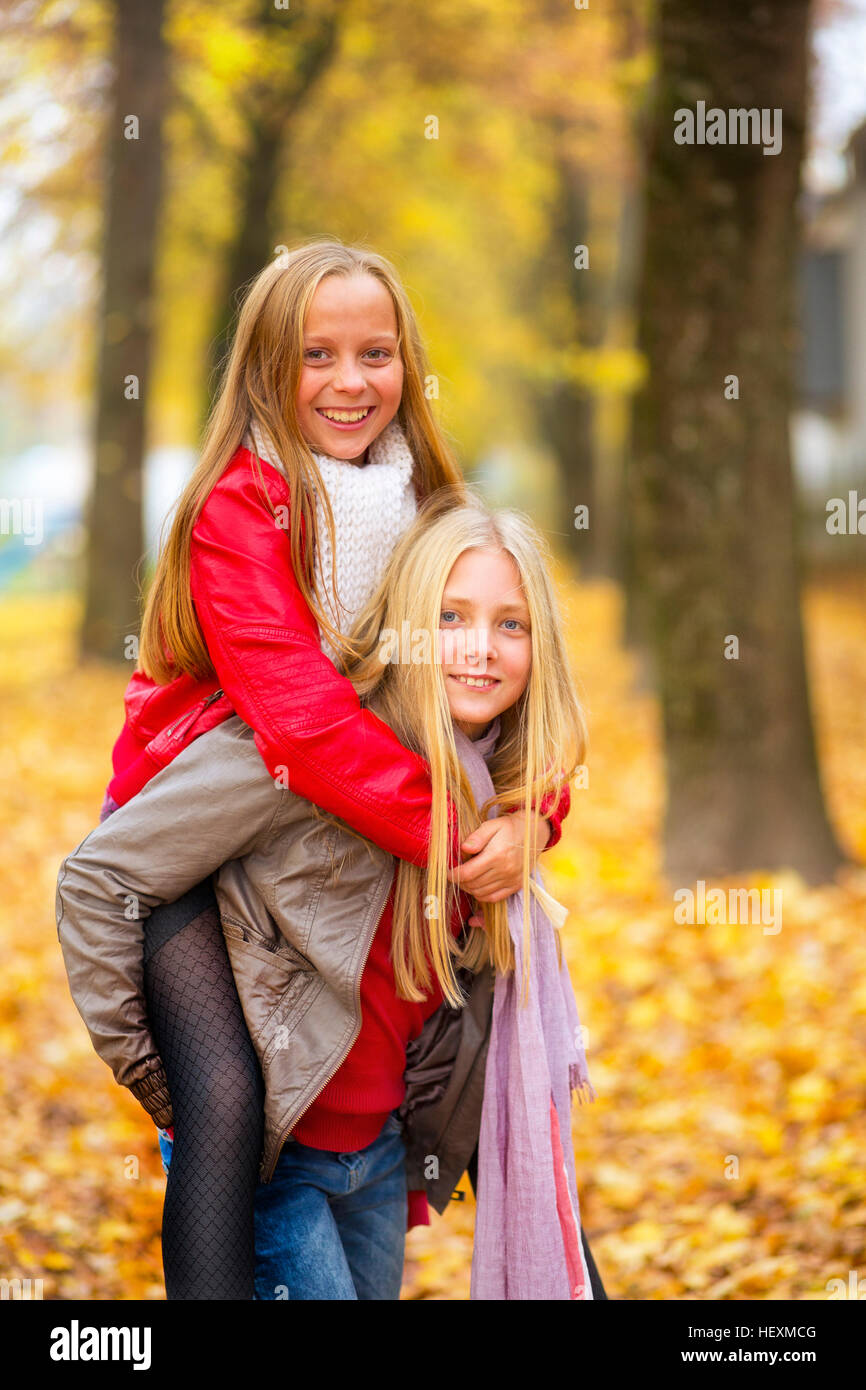 Geben ihrer besten Freundin eine Huckepack Fahrt im Herbst Mädchen Stockfoto