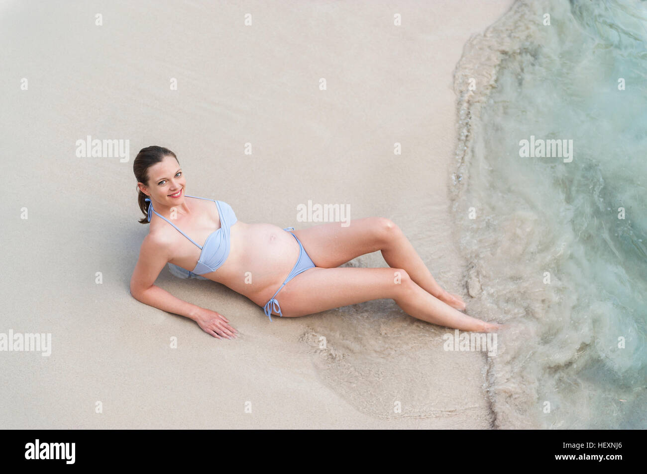 Lächelnde schwangere Frau sitzen am Meer Stockfoto