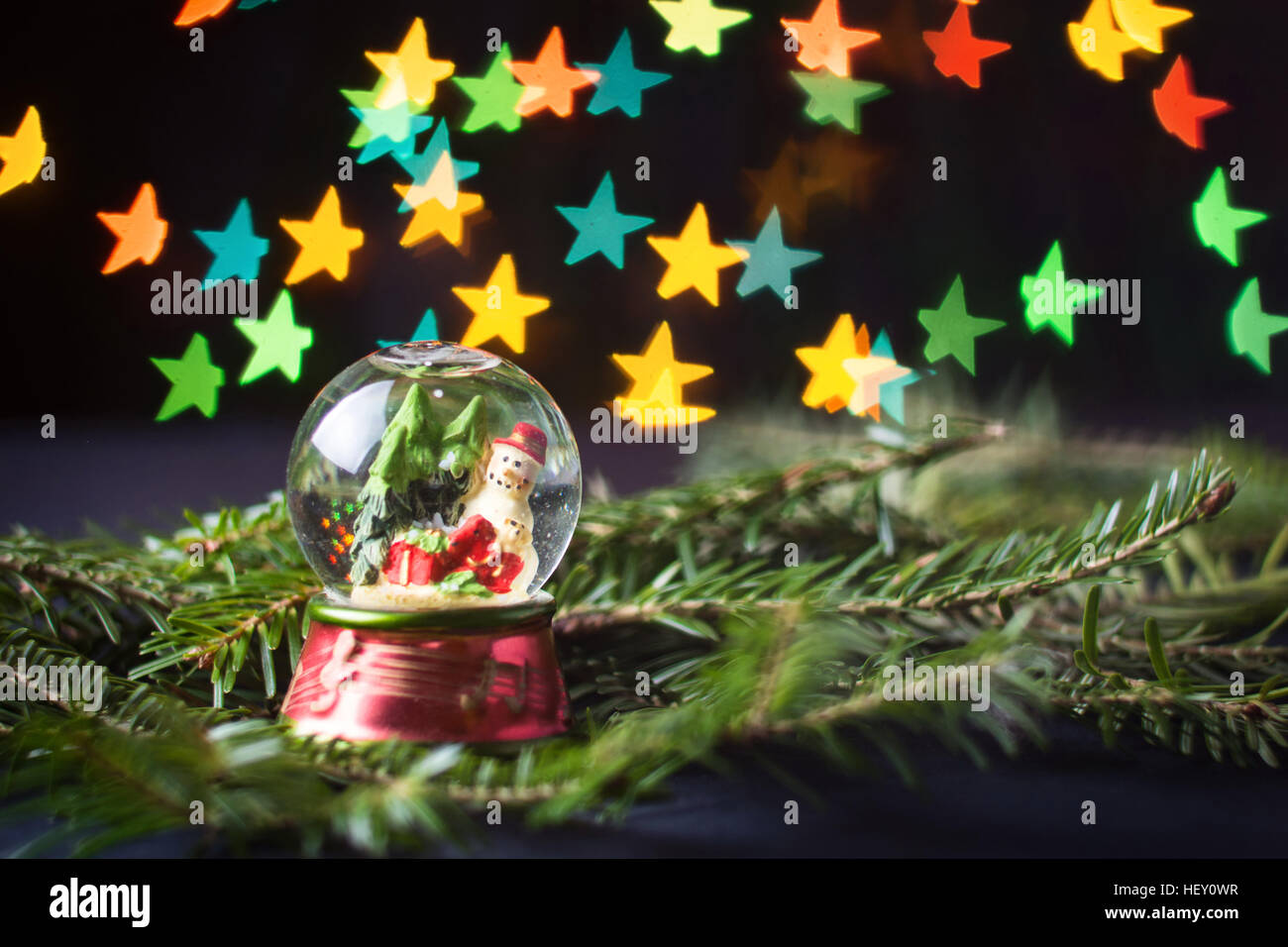 Glaskugel mit Schneemann und Sterne geformten Bokeh im Hintergrund Stockfoto