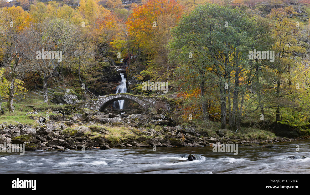 Ein Wasserfall fließt unter einer alten steinernen Lastesel Brücke entlang Glen Lyon Stockfoto