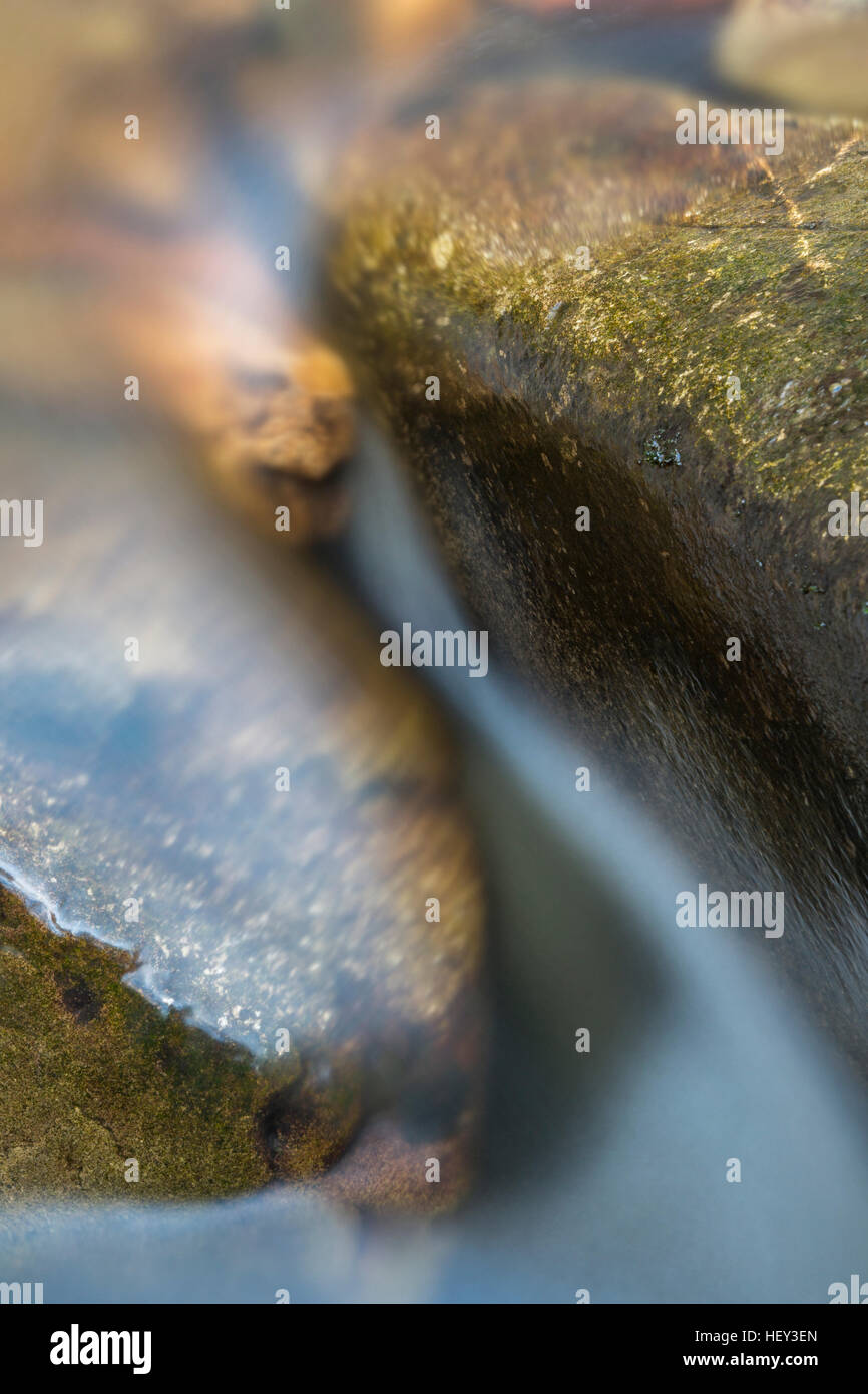 Fluss Llech fließt um zwei Felsbrocken, die Schaffung einer abstrakten Fotografie. Stockfoto