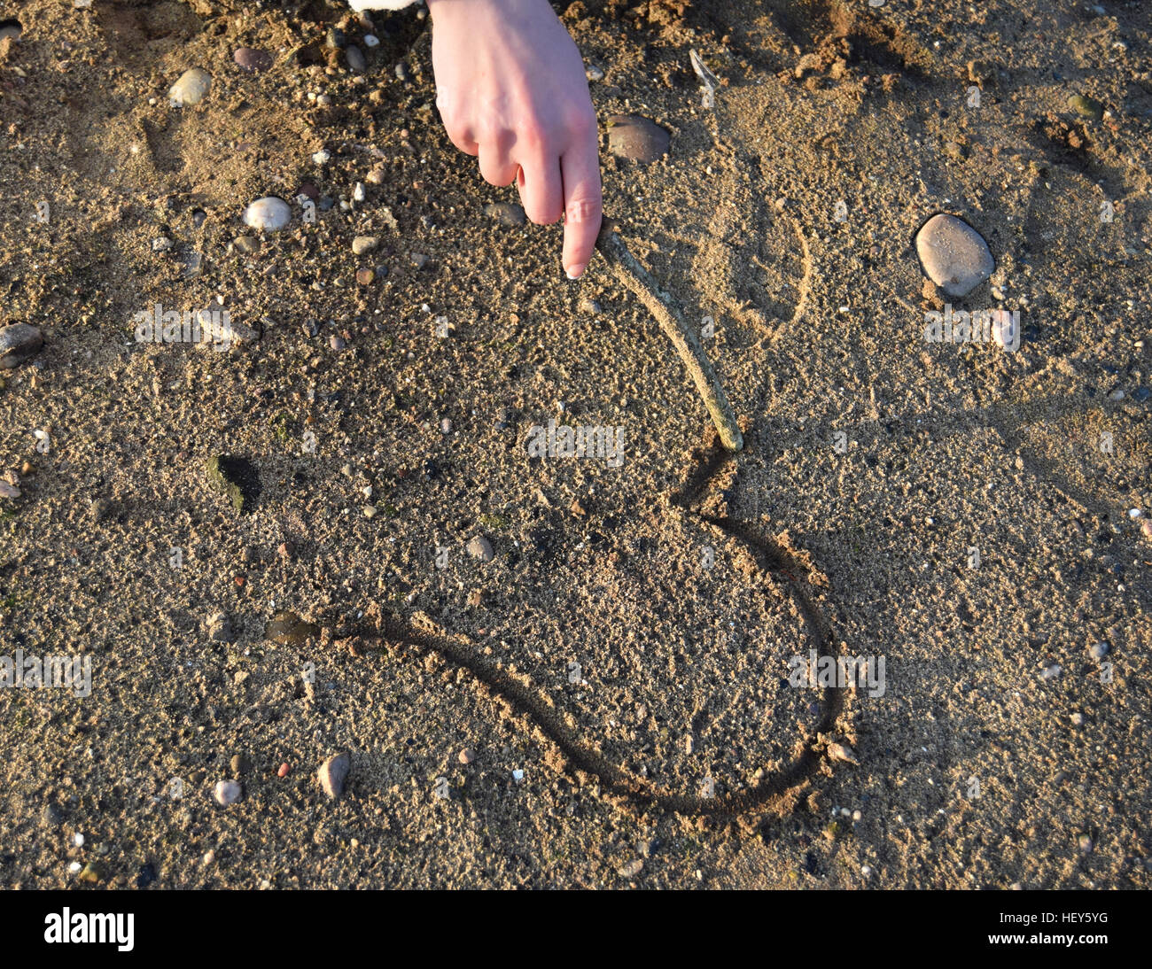 Frau hand zieht ein Herz in den Sand. Stockfoto