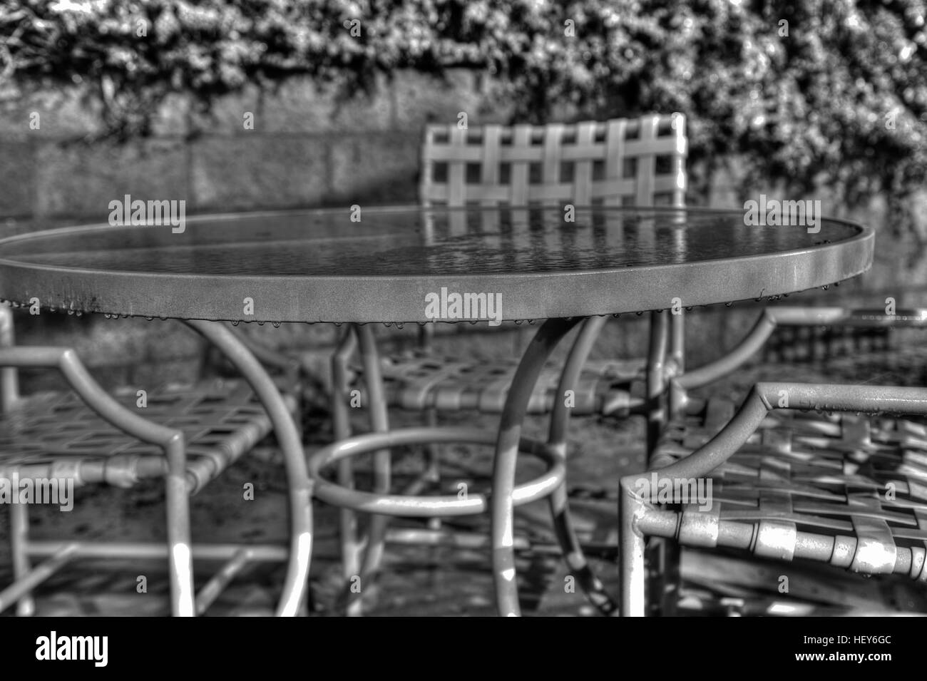 Terrassentisch und Stühle im Regen am Morgen nass. Stockfoto