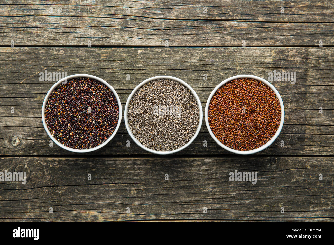 Rote und schwarze Quinoa und Chia Samen in Schüssel auf alten Holztisch. Ansicht von oben. Stockfoto