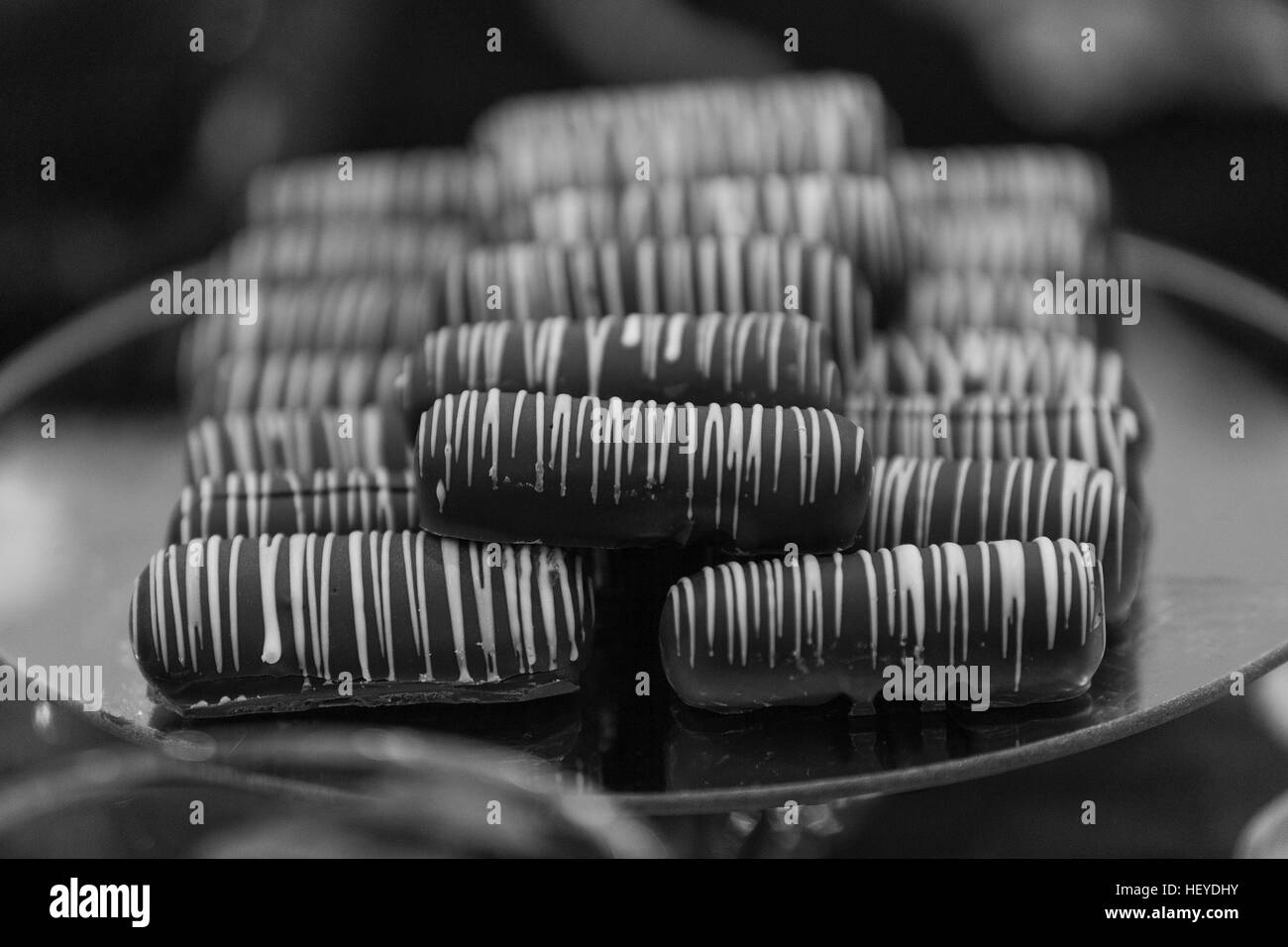 Schokolade Finger beträufelt mit weißem Zuckerguss gestapelt auf einem Teller, Monochrom Stockfoto