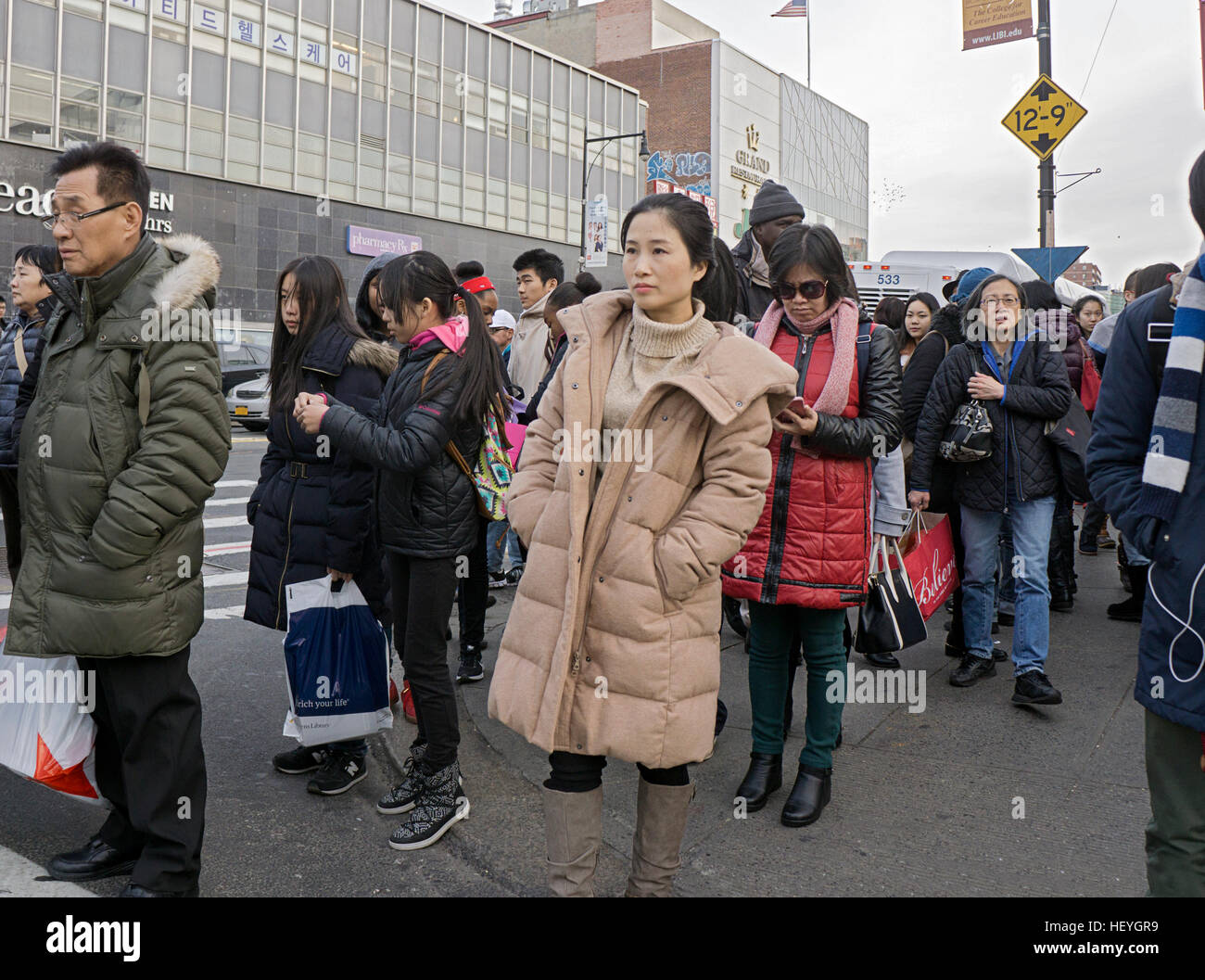 Eine attraktive Asiatin in einer Menschenmenge auf einem Bus auf der Main Street in Chinatown, Downtown Flushing, Queens, New York Stockfoto