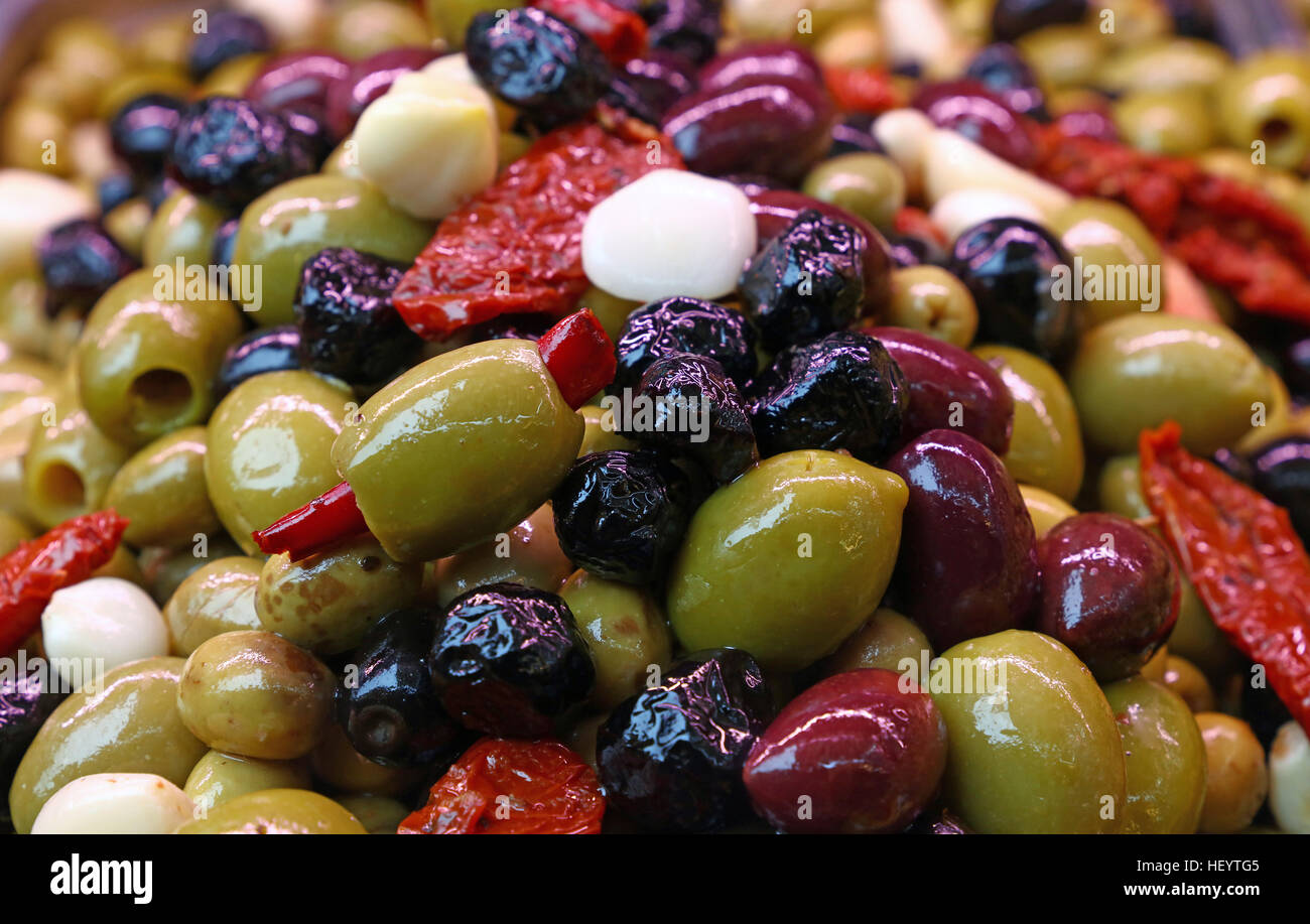 Mediterraner Salat-Mix von sortierten ganzen italienischen Oliven (schwarz, grün, rot) mit Knoblauch, Paprika und getrocknete Tomaten in Öl zu schließen, bis, low angle vi Stockfoto