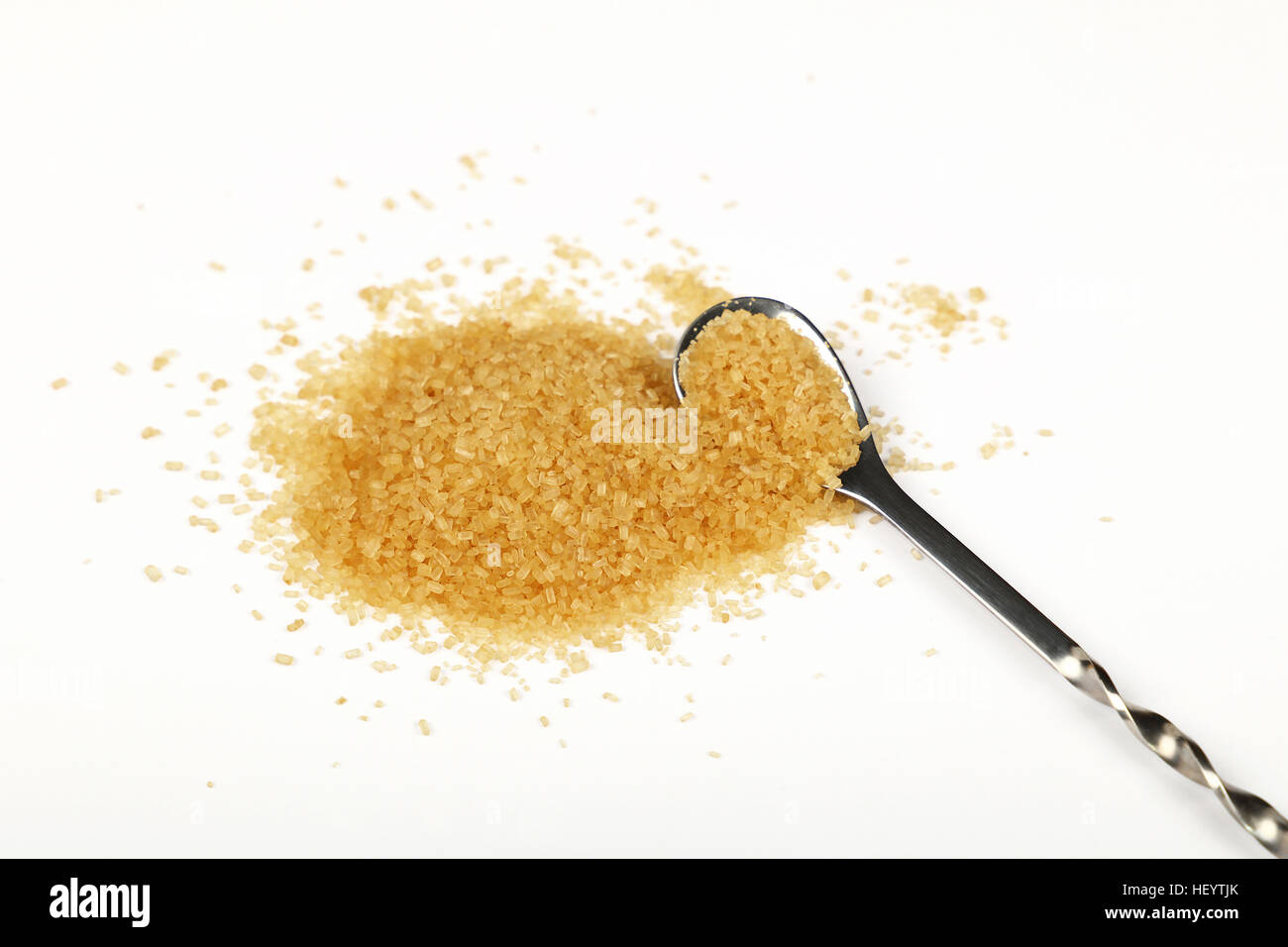 Metalllöffel voller brauner Rohrzucker mit Prise Zucker verschüttet um isoliert auf weißem Hintergrund, Nahaufnahme, hoher Winkel Stockfoto