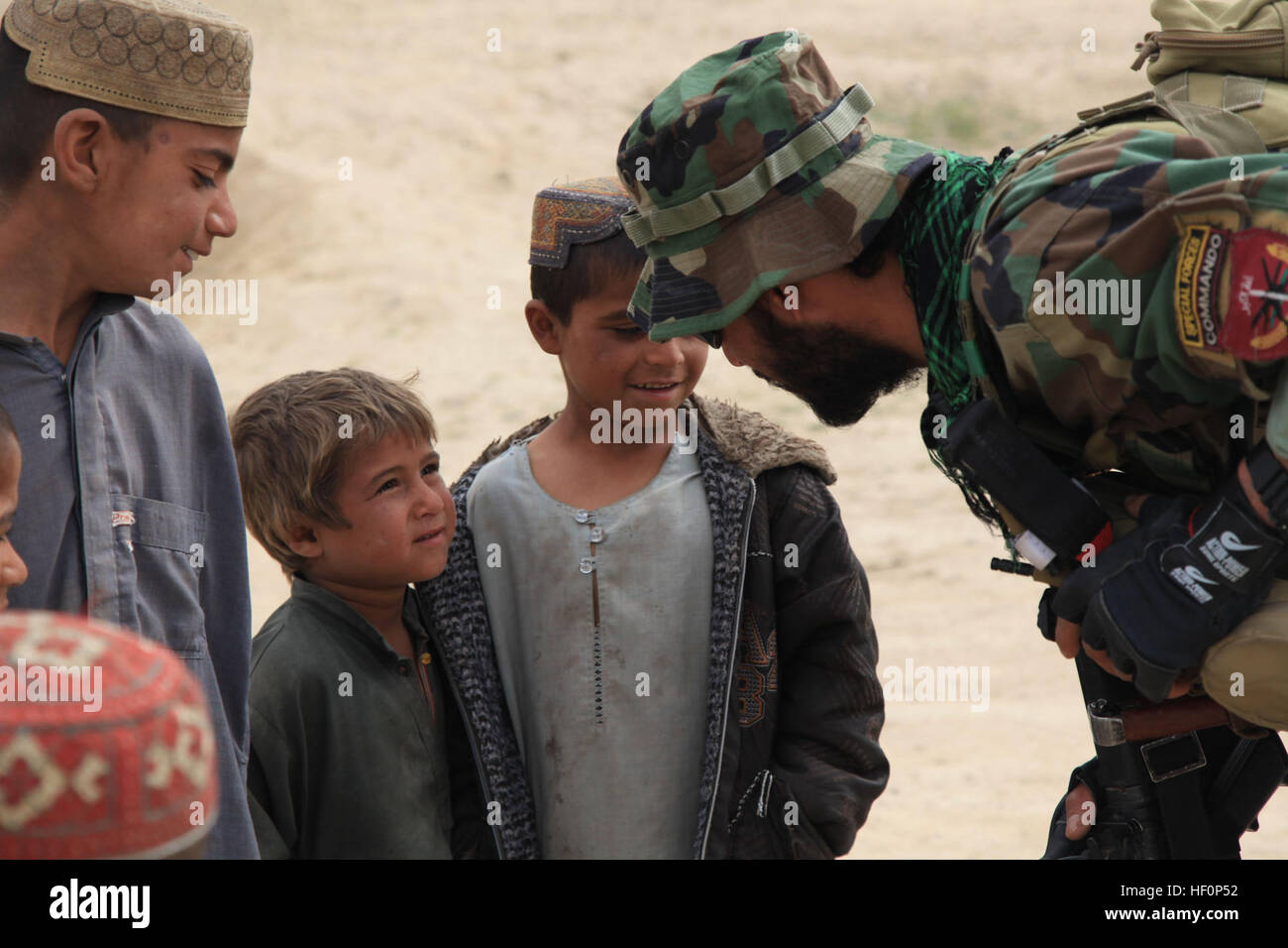 Ein Afghan National Army Special Forces Soldat spricht mit einem lokalen jungen während einer Patrouille Präsenz in Mirmandab Dorf, Provinz Helmand März 15. ANASF Soldaten und afghanische Polizei verteilt Radioprogramm hören Bücher und Radios zu Mirmandab Dorfbewohner um die Bildung in der Region zu fördern. (Offizielle Marinekorps Foto von CPL. Kyle McNally/freigegeben) ANSF verbessern Bildung in der Provinz Helmand 120315-M-EL893-026 Stockfoto