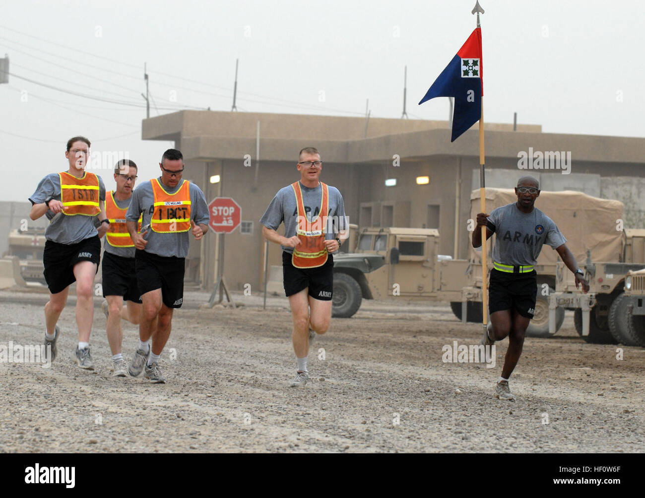 1st Sgt. Reuben Tull hisst die zentrale und Sitz Ablösung Guidon als seine Teamkollegen, Generalmajor Dave Olson, Oberstleutnant Jeffrey Mullins, Generalmajor Christopher Taylor, 1st Lt. Katherine Fenton, nähern sich die Ziellinie in einem 5k Fun Run, 17. Mai, nach vorn Operating Base Falcon, Bagdad. Drei Teams aus der 1. Brigade Combat Team, 4. US-Infanteriedivision, Multi-National Division - Bagdad, fertige hinter dem 1. Platz Team von Firma F, befestigt das 2nd Brigade Combat Team, 3. US-Infanteriedivision in der Flucht. Die Falcon 5 km Fun Run wurde gesponsert durch die nach vorne Operating Base Moral, Wohlfahrt Stockfoto