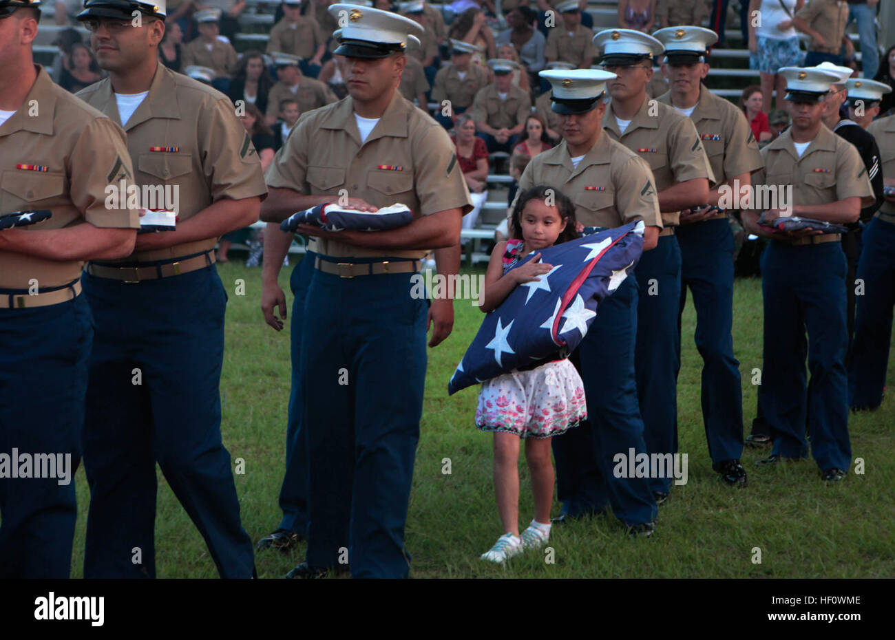 Die Tochter von einem 2. niedrige Höhe Luft Verteidigung Bataillon Marine eine amerikanische Flagge, trägt ein zeremoniellen Feuer hier. US Flag Code bestimmt, dass "Die Flagge, wenn es in einem solchen Zustand ist, dass es nicht mehr eine passende Emblem für die Anzeige, sollte würdevoll, vorzugsweise durch die Verbrennung zerstört werden." Marine Corps Air Station Cherry Point Jahresrückblick 120614-M-EG384-163 Stockfoto