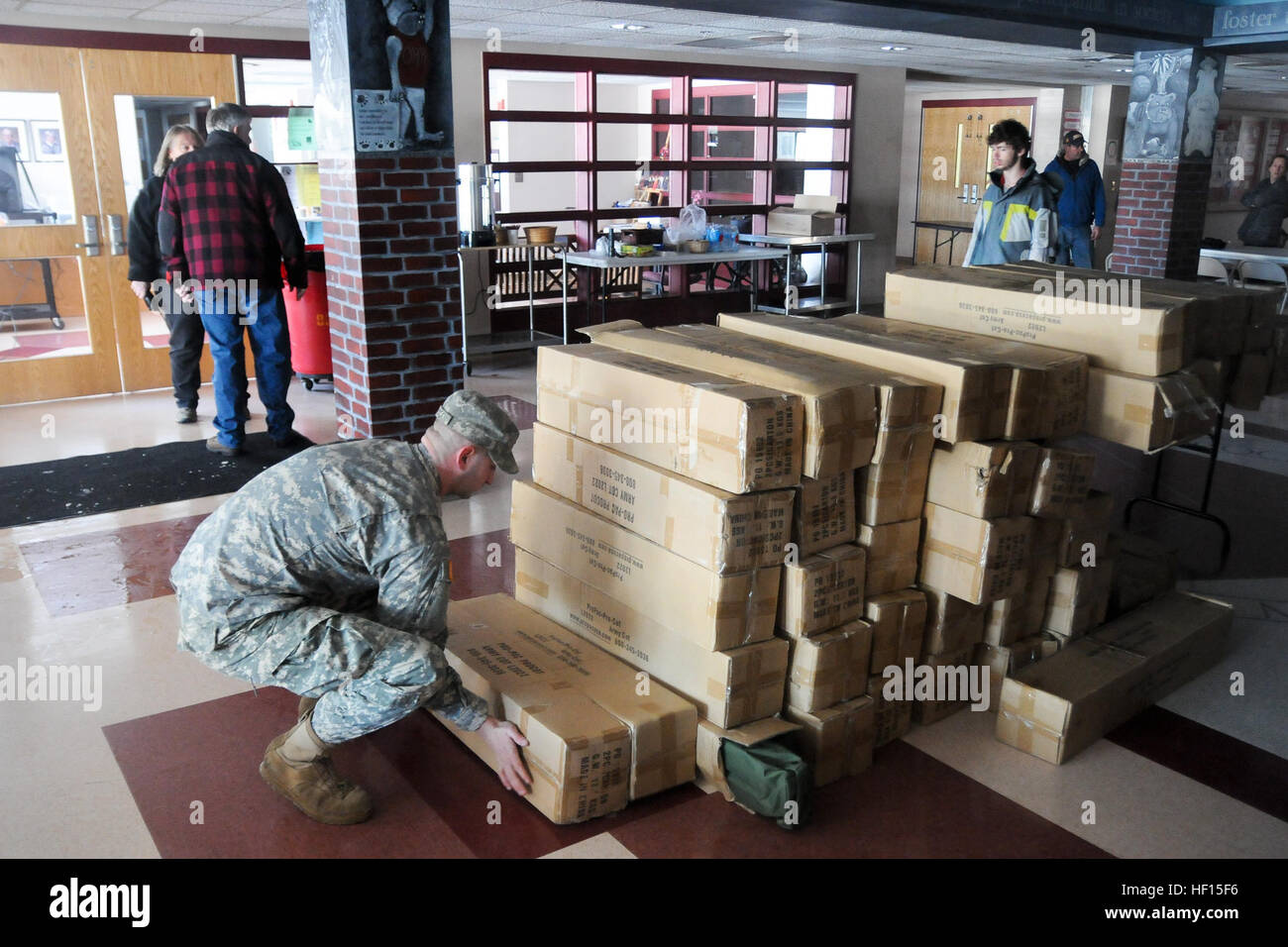 US Army Spc Justin Wilcox, links, mit 1166th Transportation Company, Massachusetts Army National Guard aus Worchester, Massachusetts, fällt ab der letzten 50 Sätze von Kinderbetten, Decken und schlafenden auf ein Wohngebiet Hilfsmission Rochester Regional Oldschool-Pads in der Nachmahd des Winter Sturm Nemo am Mattapoisett, Mass., 10. Februar 2013. John Nugent, steht im Hintergrund und seiner Familie verbrachte die Nacht in der Schule nach aus ihrer Heimat wegen Stromausfällen vertrieben werden. (US Armee-Foto von Sgt. Evan V. Lane/freigegeben) Nemo 130210-Z-KM772-014 Stockfoto