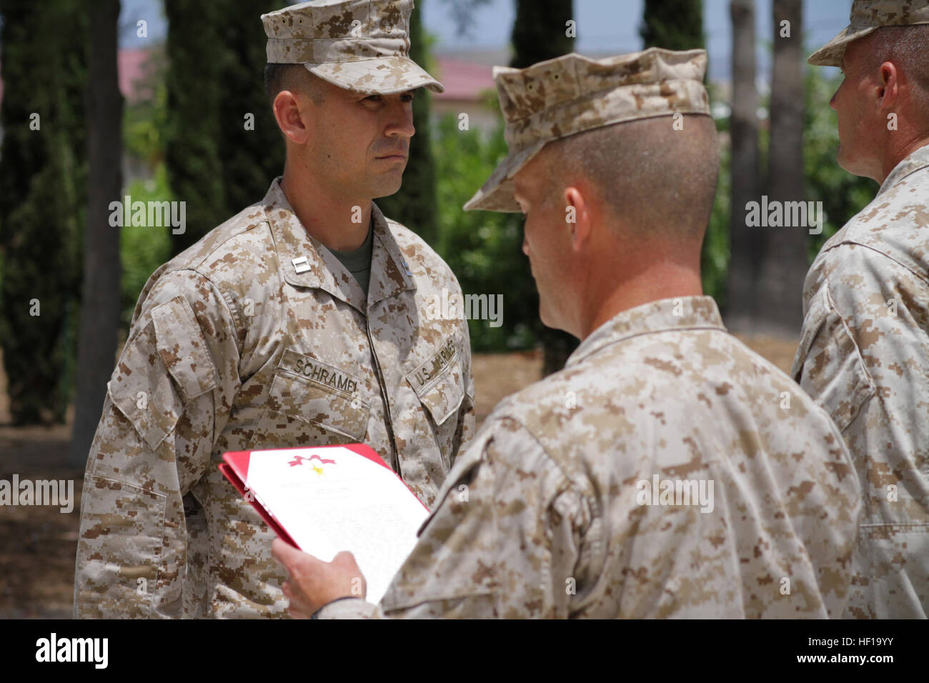 Kapitän Ryan D. Schramel, der ehemalige Kommandant der Waffen Company, 2. Bataillon, 4. Marine Regiment, steht vor einer Formation von Marines als Sgt. Major Gary T. Bow, die Bataillons-Sergeant-Major, liest Schramels Award Zitat für den Bronze Star Medal mit Kampf "V" für Tapferkeit im Rahmen einer Feierstunde im 5. Marines Memorial Garden, 16. Mai 2013. Schramel, gebürtig aus Taylorsville, Calif., erhielt den Bronze Star für die Führung seines Unternehmens der Marines durch mehrere Kampfhandlungen und Kämpfe mit Aufständischen in der jetzt Zad Bezirk der Provinz Helmand, Afghanistan. D Stockfoto