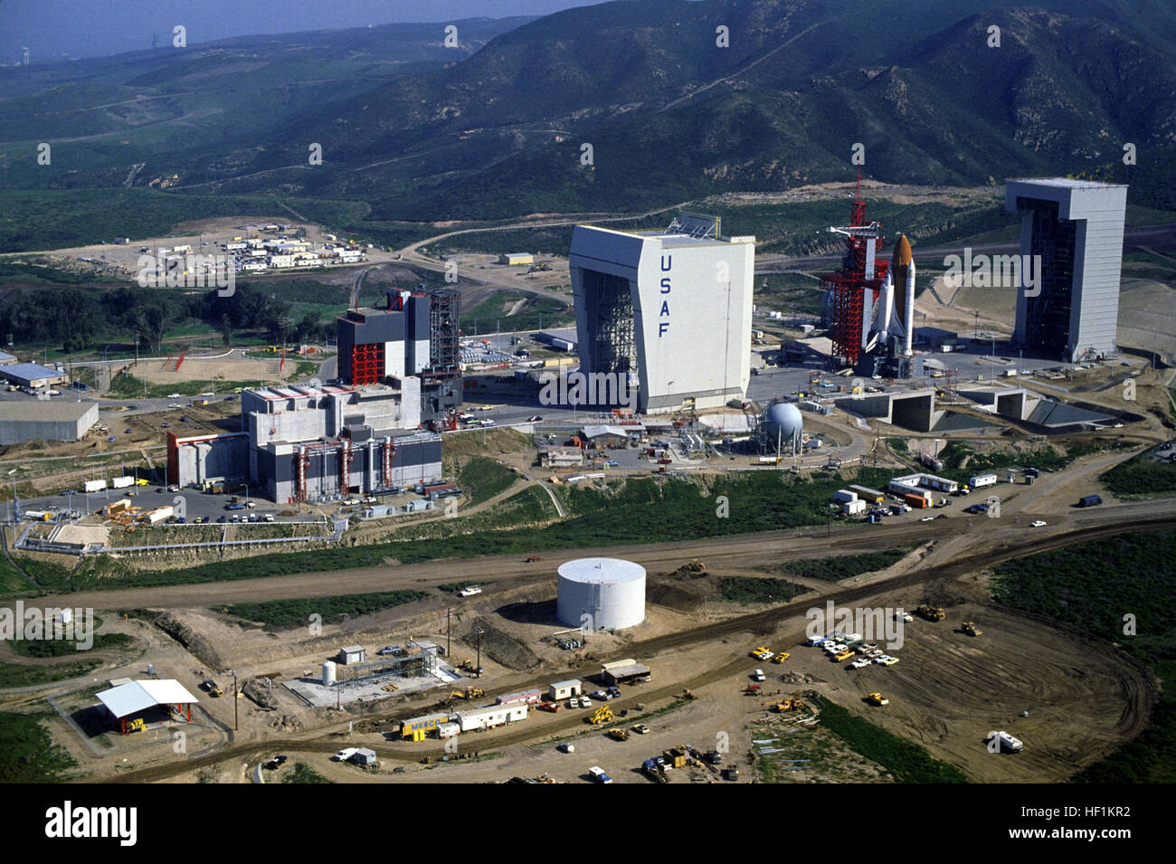 Einen allgemeinen Überblick über Space Launch Complex sechs.  Die Strukturen sind von links nach rechts: die Nutzlast Batterietüre Zimmer angeschlossen, der Shuttle Montagehalle, der Zugang Turm und Start Berg, und der mobile Service Tower.  Das Space Shuttle Enterprise, verbunden mit einem Außentank und Feststoffraketen, ruht auf der Start-Halterung. Vandenberg Raketenstart AFB komplexe 6 1985 (mit Unternehmen) Stockfoto