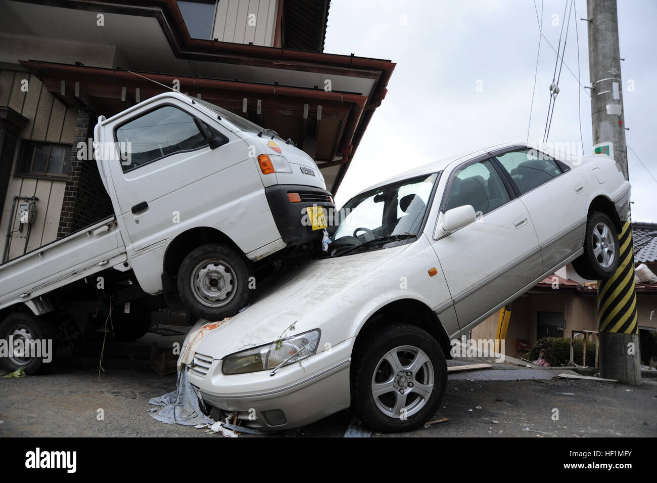 Ein Pkw liegt eingeklemmt zwischen einem Pickup-Truck und ein Lichtmast nach einem 8,9-Erdbeben, die einen verheerenden Tsunami durch die japanische Küstenstadt ausgelöst. Flickr - DVIDSHUB - Suche und Rettung Arbeiter kommen in Ofunato (Bild 13 von 23) Stockfoto