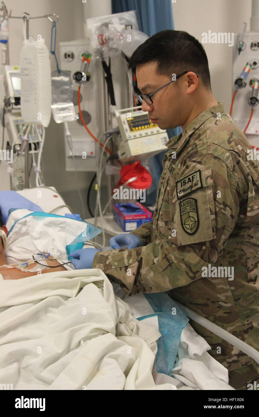 Lt. Lyndon Guo, Intensivpflege Krankenschwester bei der multinationalen medizinische Einheit, einem Krankenhaus in Kandahar Flugplatz, Afghanistan, gibt Medikamente zu einem afghanischen Kind, in einem Raketenangriff auf Samstag verletzt war, 18.Jan, 2014 in Maiwand Bezirk. (Foto: US-Armee Sgt. Antony S. Lee) Afghanische Kinder in ernstem Zustand aber lebendig nach Angriff 140120-Z-MH103-739 Stockfoto