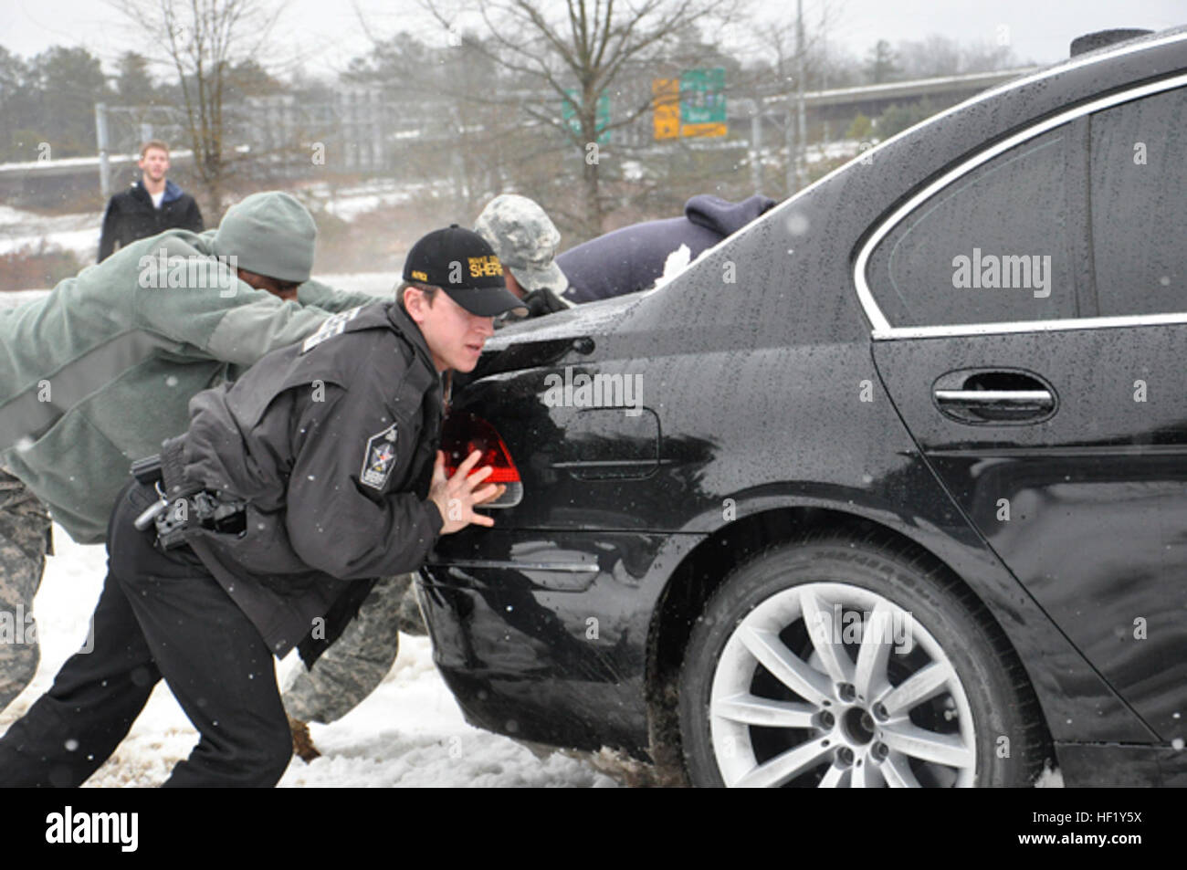PFC. Lorenzo Garrick, 113. Sustainment Brigade und stellvertretender Erik Seda, Wake County Sheriff Office, schieben ein Auto aus dem Graben entlang eine Abfahrt in Raleigh, NC, 13. Februar 2014. Die North Carolina National Guard hat Polizisten auf ihren Patrouillen im ganzen Land unterstützt. (US Army National Guard Foto von Pfc. Lisa Reben, 382nd Public Affairs Abteilung/freigegeben) NC Nationalgarde unterstützen die North Carolina Division of Emergency Management während Winter Sturm Pax 140213-Z-EH515-119 Stockfoto