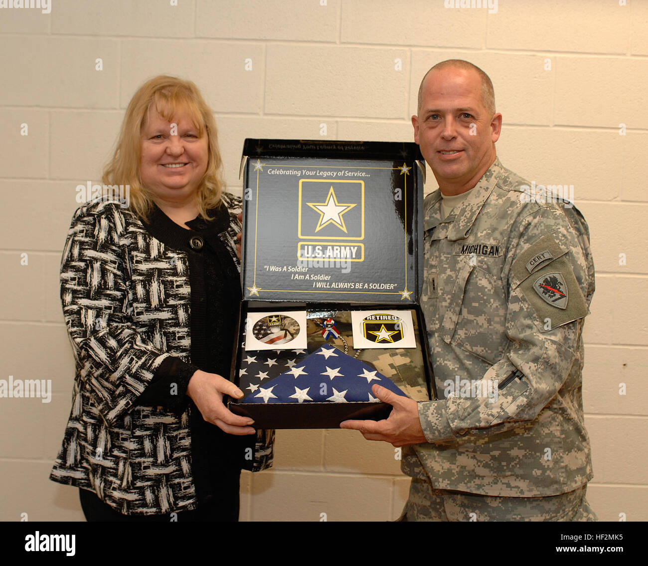 Ehemaliger US Army Reserve und ehemaligen Michigan Army National Guard Captain Teresa Dobie, erhält eine Rente Flagge und Pin Michigan Volunteer Defense Force Mitglieds, Chief Warrant Officer 3 James Jones, in Jackson, Michigan, Armory, 5. November 2014. Jones ist ein Ruhestand Dienstleistungen Spezialist mit dem Michigan National Guard gemeinsame Kräfte Hauptsitz in Lansing und unterstützt die MING Familie Programme Büro auf die Spur der förderfähigen Veteranen gerne bei der Beantragung von Leistungen. (Foto von Master Sergeant Denice Rankin, JFHQ MING, Public Affairs/freigegeben) Ehemaliger US Army Reserve und ehemaligen Michigan A Stockfoto