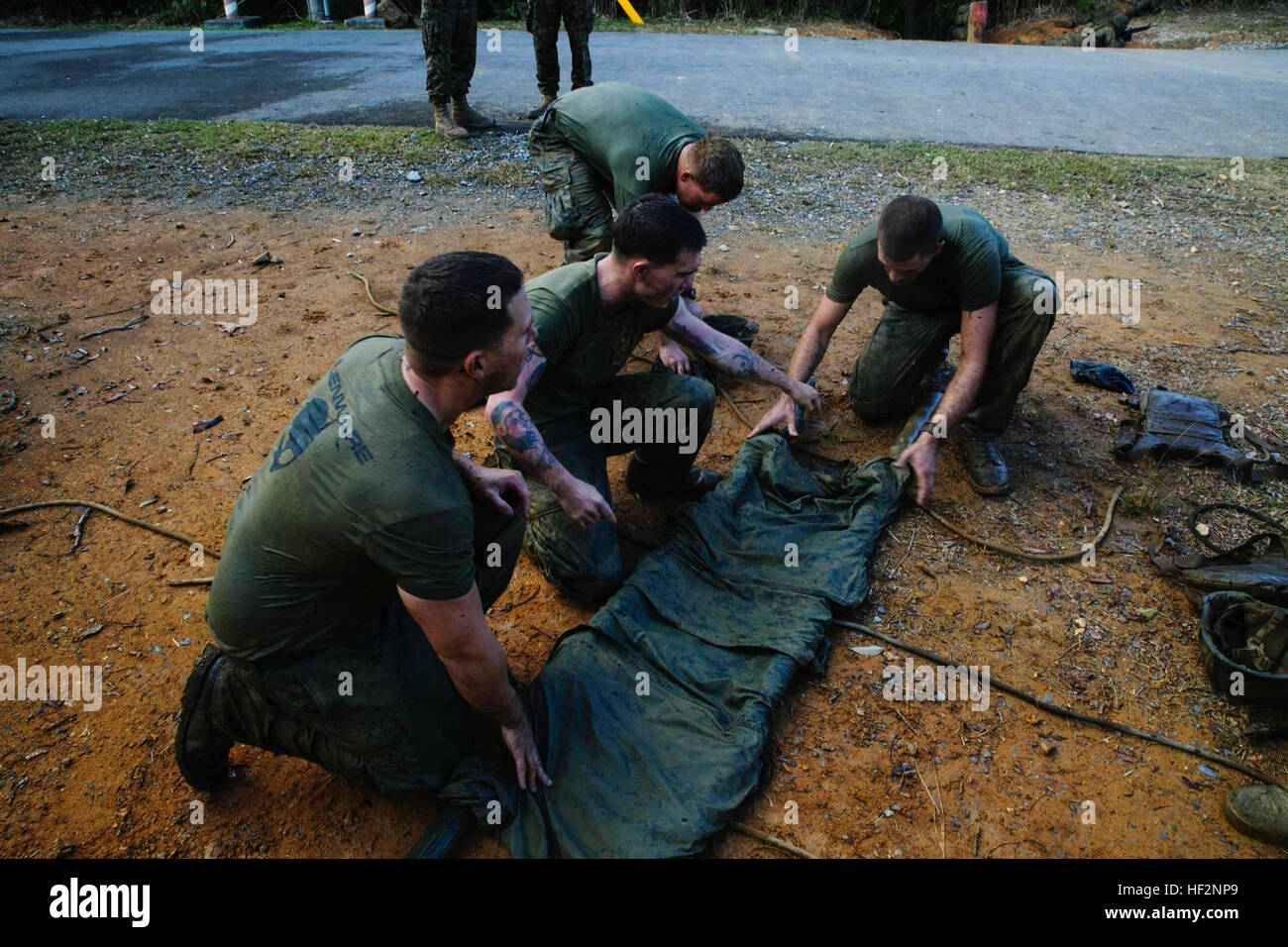 Marines machen eine improvisierte Wurf mit Stöcken, die sie fanden und ihre Blusen im Verlauf Ausdauer 25 November an der Jungle Warfare Training Center auf Lager Gonsalves. Der Ausdauer-Kurs ist ein 4-Meilen-Kurs, der Abseilen enthält, Seilbrücken, Wasserhindernisse und eine simulierte Unfall-Station. Die Marines sind mit 1. Bataillon, 1. Marineregiment, derzeit 4. Marine Regiment, 3. Marineabteilung, III. Marine Expeditionary Force, unter der Einheit-Deployment-Programm zugewiesen. (US Marine Corps Foto von CPL. Thor J. Larson/freigegeben) Marines, laufen, Schwimmen, Abseilen durch OkinawaE28099s Mou Stockfoto