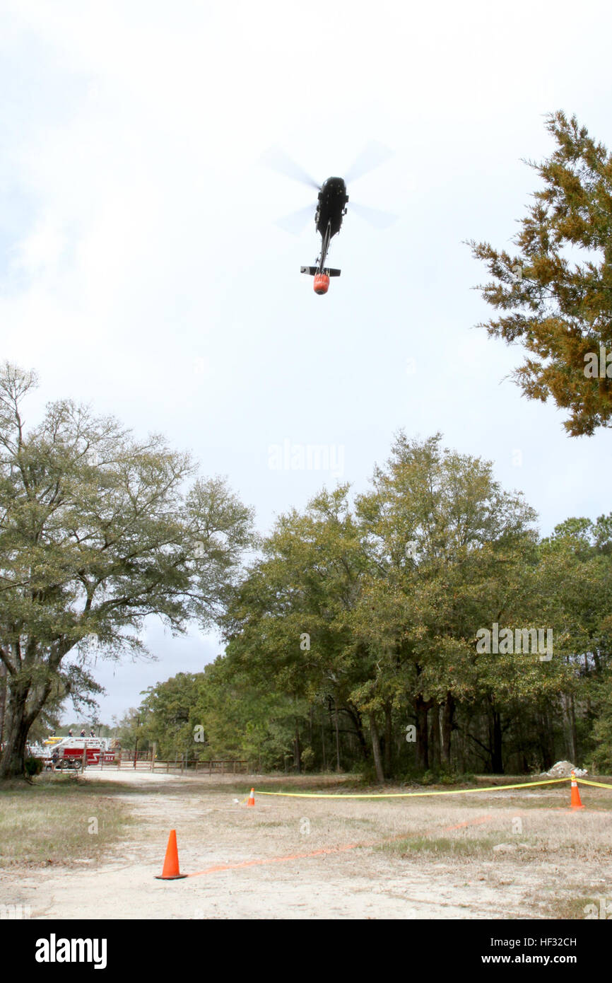 Ein UH-60 Black Hawk, mit 2-151 Aviation Battalion, S.C. National Guard, Tropfen Wasser aus einem Eimer Bambi in einer simulierten Brand während einer Übung 10. März 2015, im Stall Park, Pawley Island, S.C. im Rahmen der wachsam Garde. Wachsam Guard ist eine Reihe von staatlich geförderten Katastrophenabwehr Bohrer von Einheiten der Nationalgarde in Zusammenarbeit mit Bund, Ländern und Gemeinden Notfallmanagement Agenturen und Ersthelfer durchgeführt. (US Army National Guard Foto von Sgt. Brad Schwuchtel/freigegeben) SC-Guard begießst gefährliche Flammen während des Trainings Übung 150310-Z-WS267-003 Stockfoto