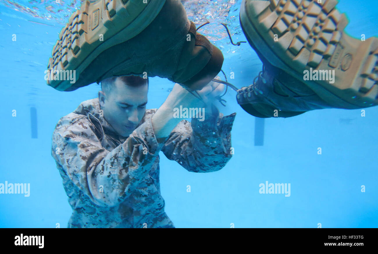 Sgt. Nicholas P. Slover, ein US-Marine mit der 26. Marine Expeditionary Unit entfernt sein Boot vor dem Aufblasen seine Hose während einer Qualifikation Schwimmstrecke am Pool Bereich 5 an Bord der Marine Corps Base Camp Lejeune, North Carolina, 17. März 2015. Marines müssen Wassertreten für 10 Minuten während der Qualifikation nachweisen, dass sie ordnungsgemäß ihre Uniform als eine Schwimmhilfe für das Überleben im Wasser verwenden können. (U.S. Marine Corps Foto von Staff Sgt. Bobby J. Yarbrough/freigegeben) Wasser überleben 150317-M-DE426-003 Stockfoto