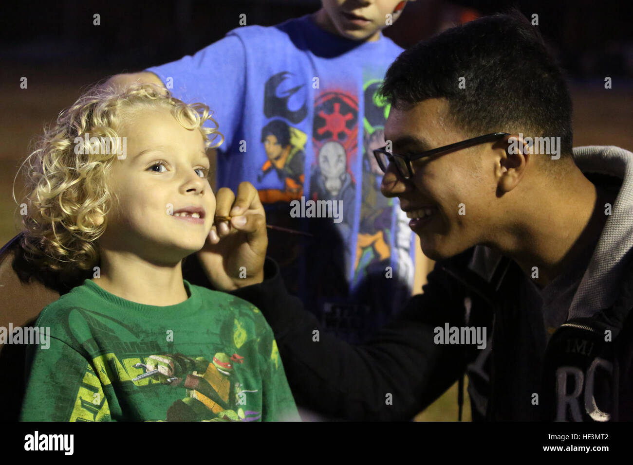 Jackson, ein 6-jährige, lächelt als Lance Cpl. Yoshio Galindo malt eine Design auf seinem Gesicht während Familie Herbstfest veranstaltet von Marine Air Control Squadron 2 im Marine Corps Air Station Cherry Point, North Carolina, 22. Oktober 2015. Mehr als 100 Marines, Segler und Familienmitglieder trafen sich zum Auftakt der Herbstsaison mit einem Chili Cook-off- und Kostüm-Wettbewerb sowie Spiele, einen Film und ein Lagerfeuer. Galindo ist der Spezialist für ein Flugzeug-Verwaltung. (U.S. Marine Corps Foto von CPL. N.W. Huertas/freigegeben) MACS-2 Marines, Familien sind herzlich willkommen Herbst mit Herbst Familie Festival 151022-M-RH401-050 Stockfoto