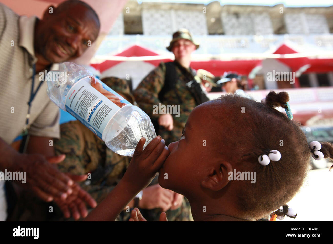 Eine haitianische Mädchen Ausführungen gab eine Flasche Wasser-Service-Mitglieder ihr an einem humanitären Hilfe medizinische Standort Saint-Louis-du-Nord, Haiti, am 27. Juli 2010. Operation Continuing Promise 2010 ist eine kooperative Bemühung, die militärische und zivile Personal für humanitäre Hilfe und Katastrophenschutz, Karibik, Mittel- und Südamerika umfasst. Betrieb weiterhin Versprechen 2010 DVIDS307192 Stockfoto